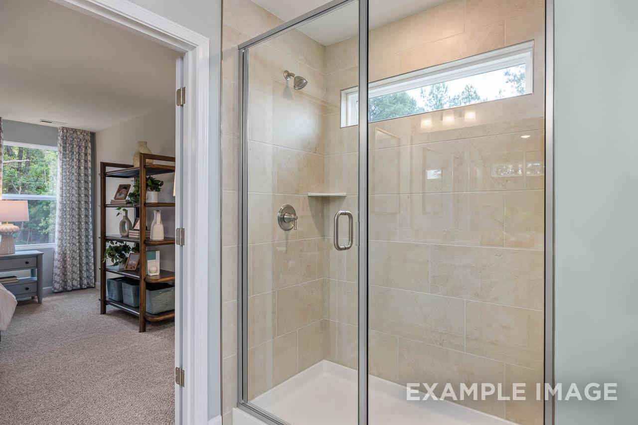 Glass walk-in shower with beige tile in The Willow C-BF master bathroom by Davidson Homes in Mt. Juliet, TN.