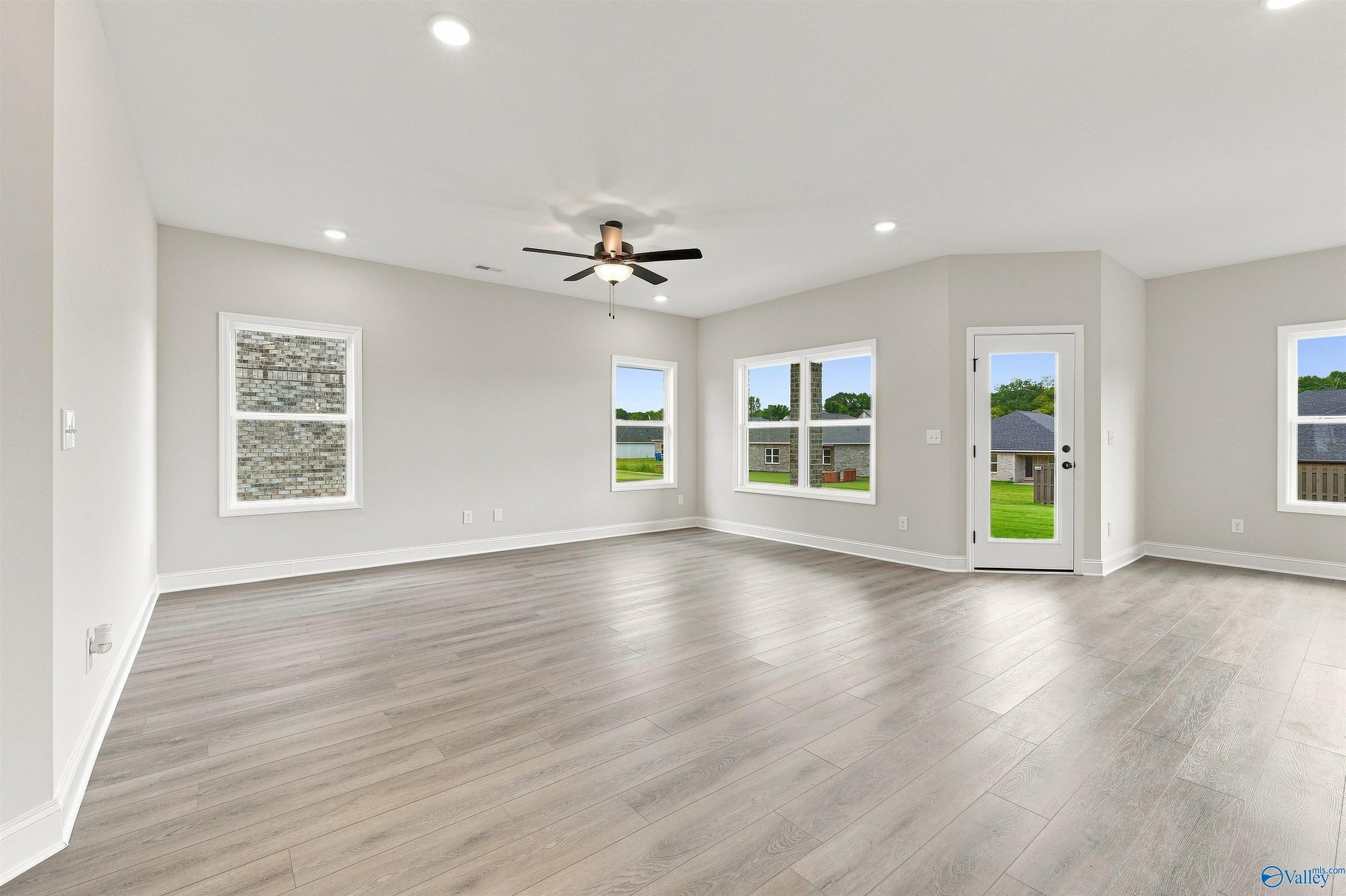 Bright open-concept great room with luxury vinyl plank flooring, ceiling fan, and backyard access in Davidson Homes Franklin C, Athens, AL