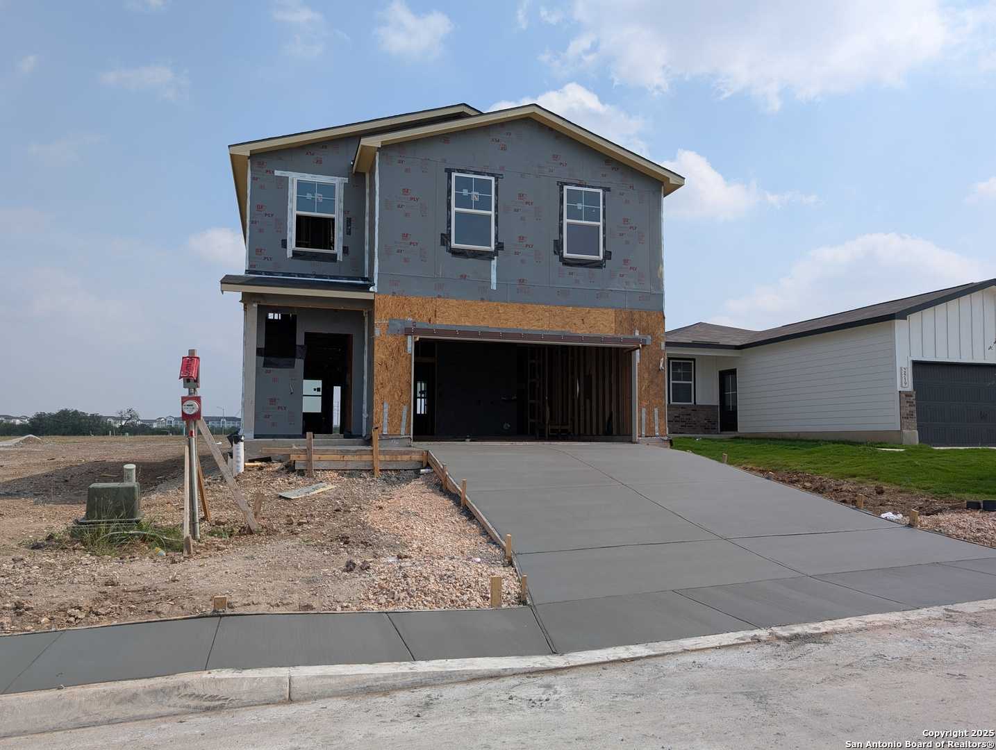 Davidson Homes The Brazos C: Two-story 5-bedroom gray home under construction with open garage and driveway in Applewhite Meadows, San Antonio, Texas