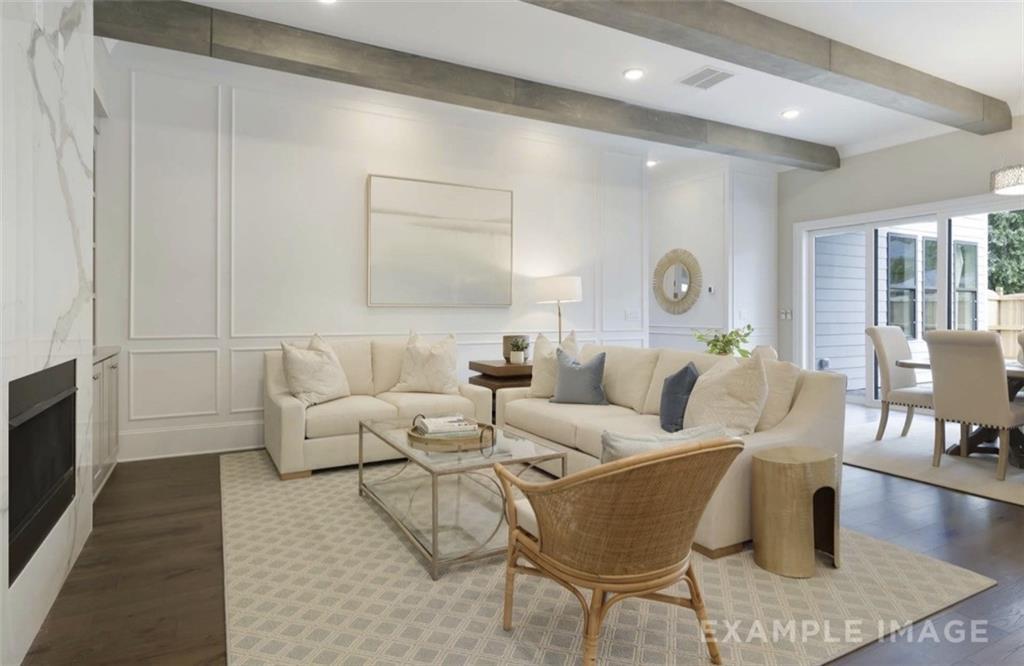 Elegant living room with exposed beams, white wainscoting, beige sofas, fireplace, and French doors in Davidson Homes The Seaside A, Woodstock, GA