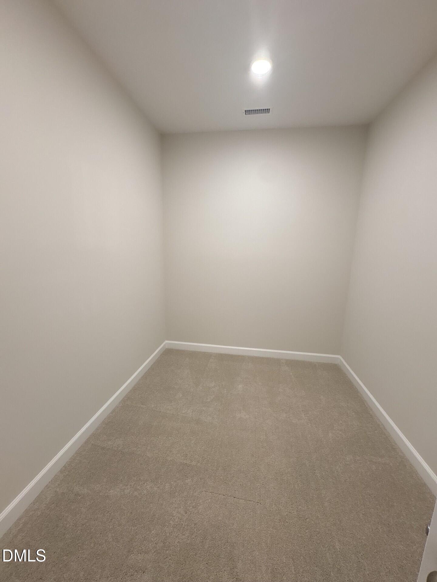 Spacious walk-in closet with neutral carpet and recessed lighting in The Ash C floor plan at Woodland Crossing, Zebulon, NC.