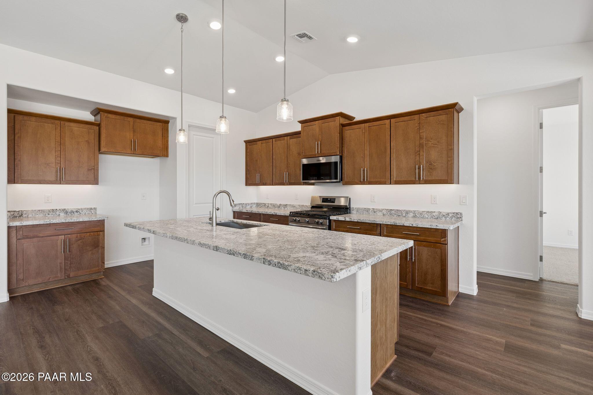 Modern kitchen featuring granite island, stainless appliances, and wood cabinets in Davidson Homes The Monarch A, Prescott, AZ