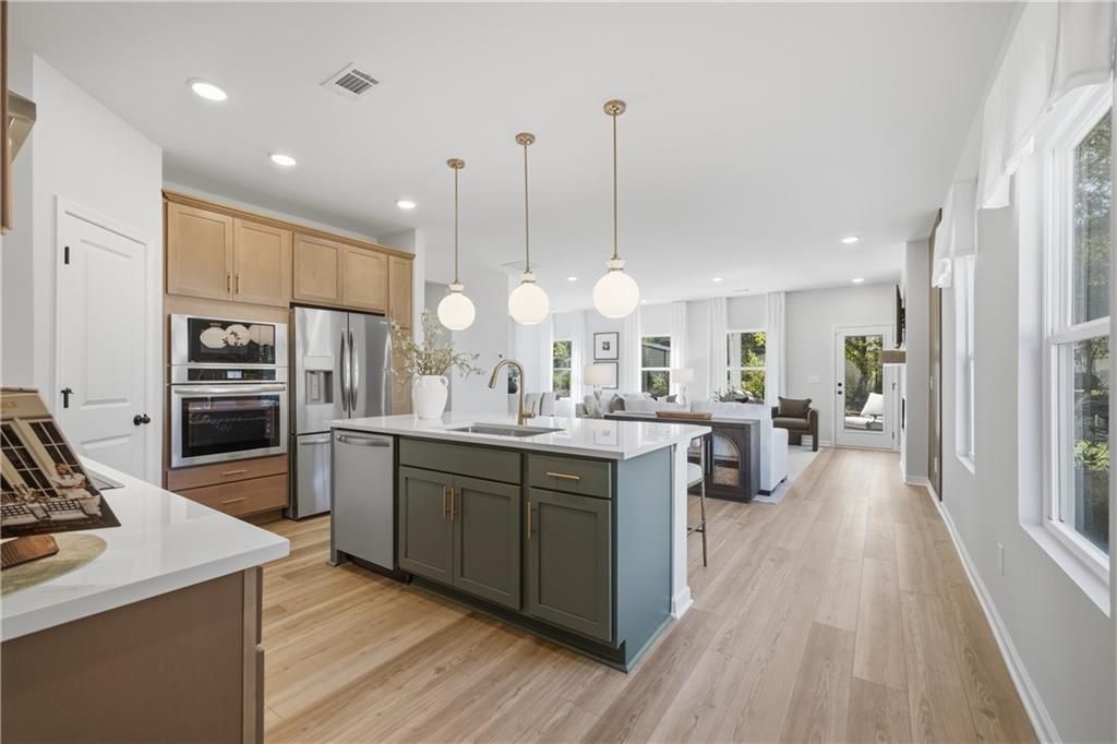 Modern kitchen with green island, stainless appliances, and pendant lights in Davidson Homes Sinclair B plan, Cartersville, GA