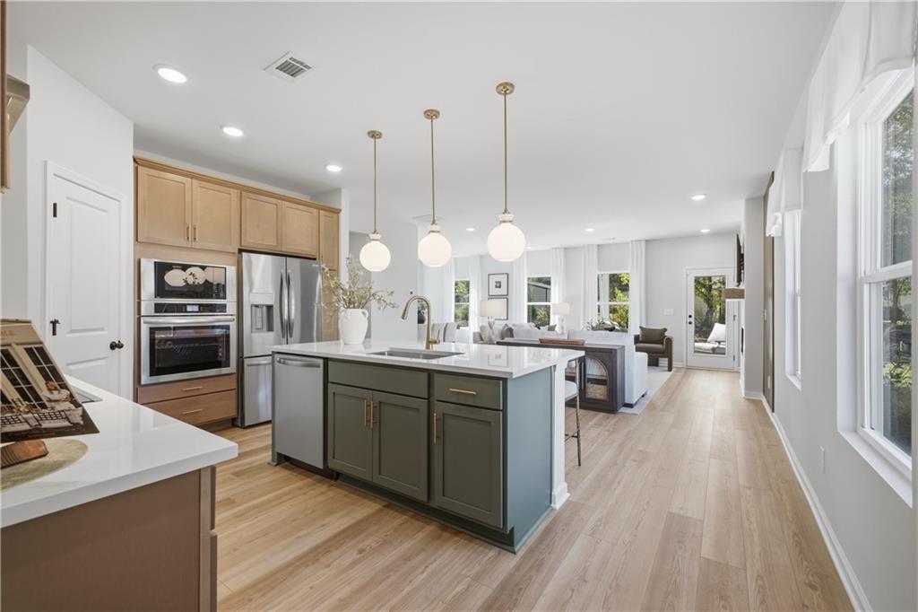 Open-concept kitchen with green island, wood cabinets, and pendant lighting in Davidson Homes Sinclair B plan, Cartersville, GA