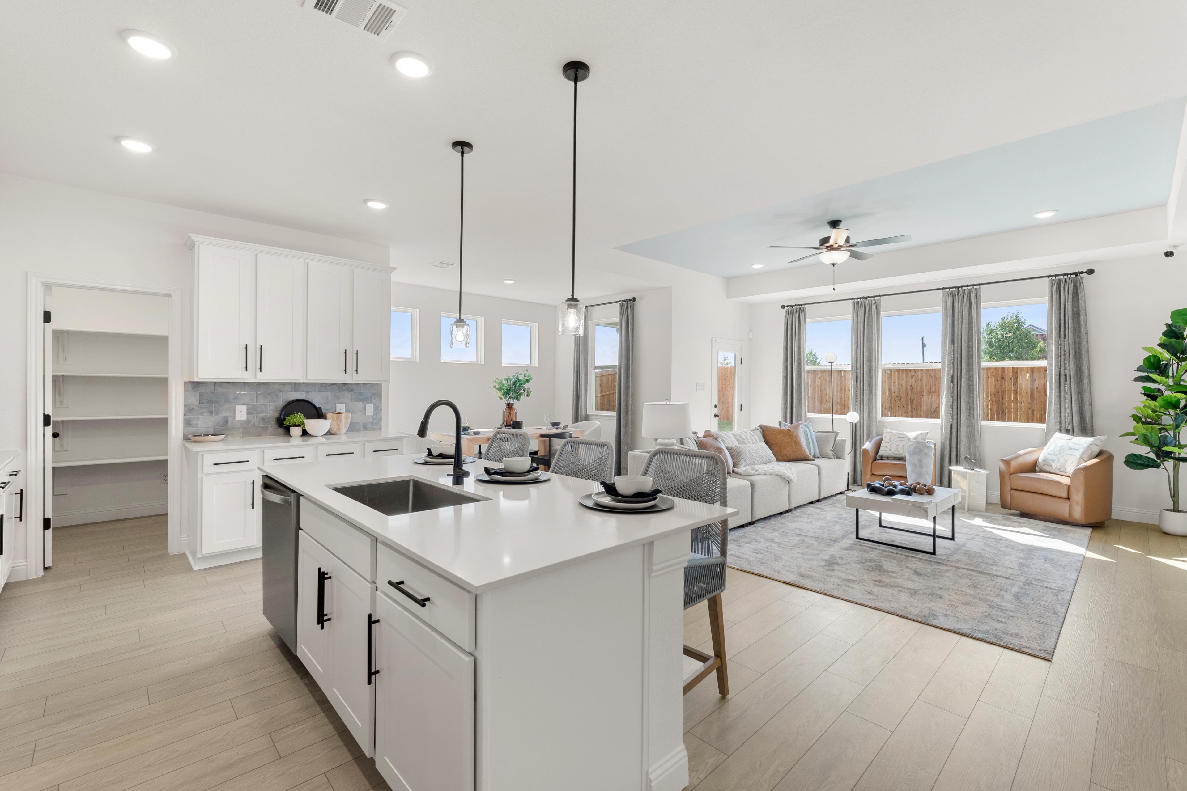 Spacious open-concept kitchen and living room at Meadow Ridge Estates in Josephine Texas with white island, hardwood floors, and large windows