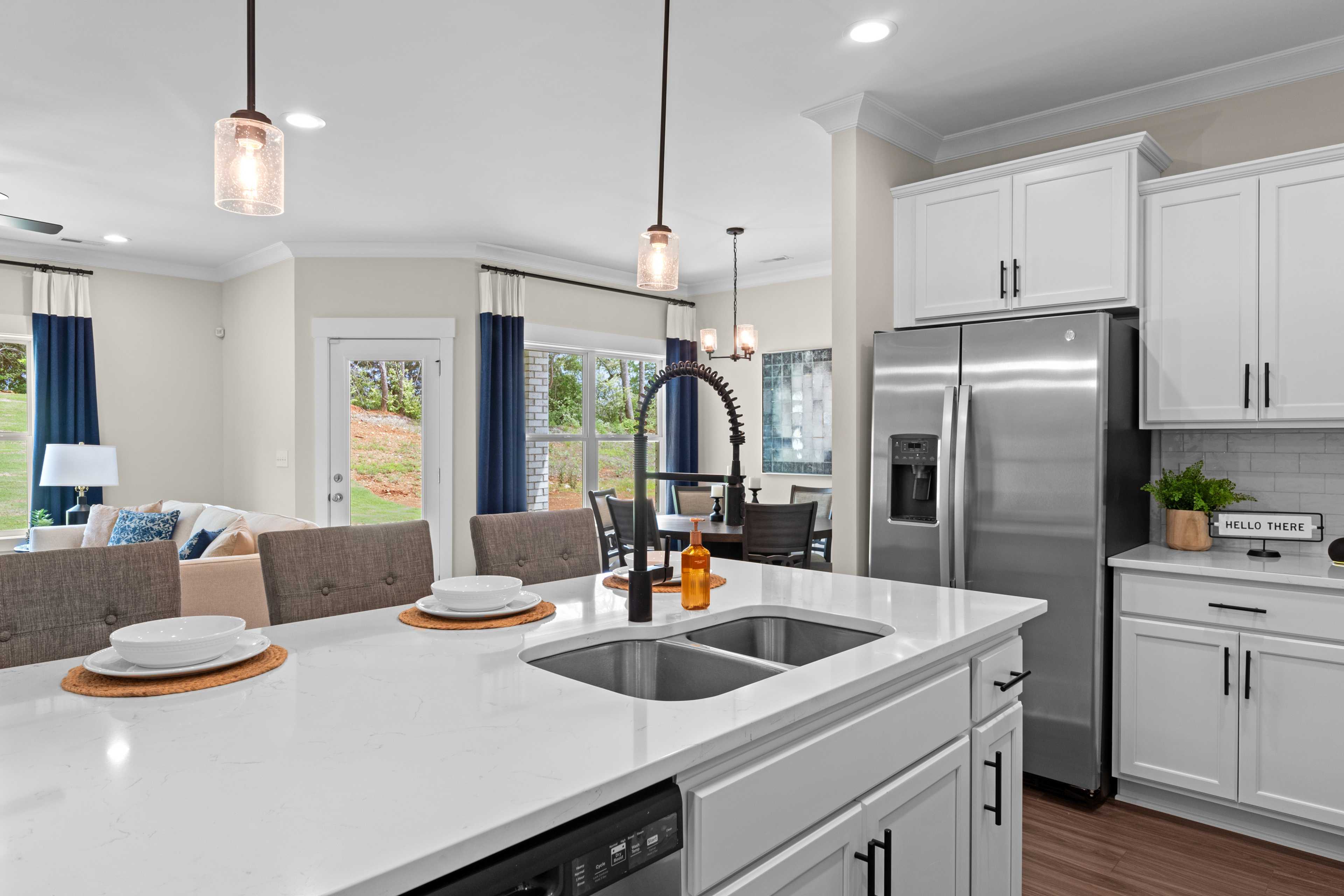 Modern kitchen in Ivy Hills Toney Alabama with white shaker cabinets, quartz island sink, stainless steel appliances, and hardwood floors