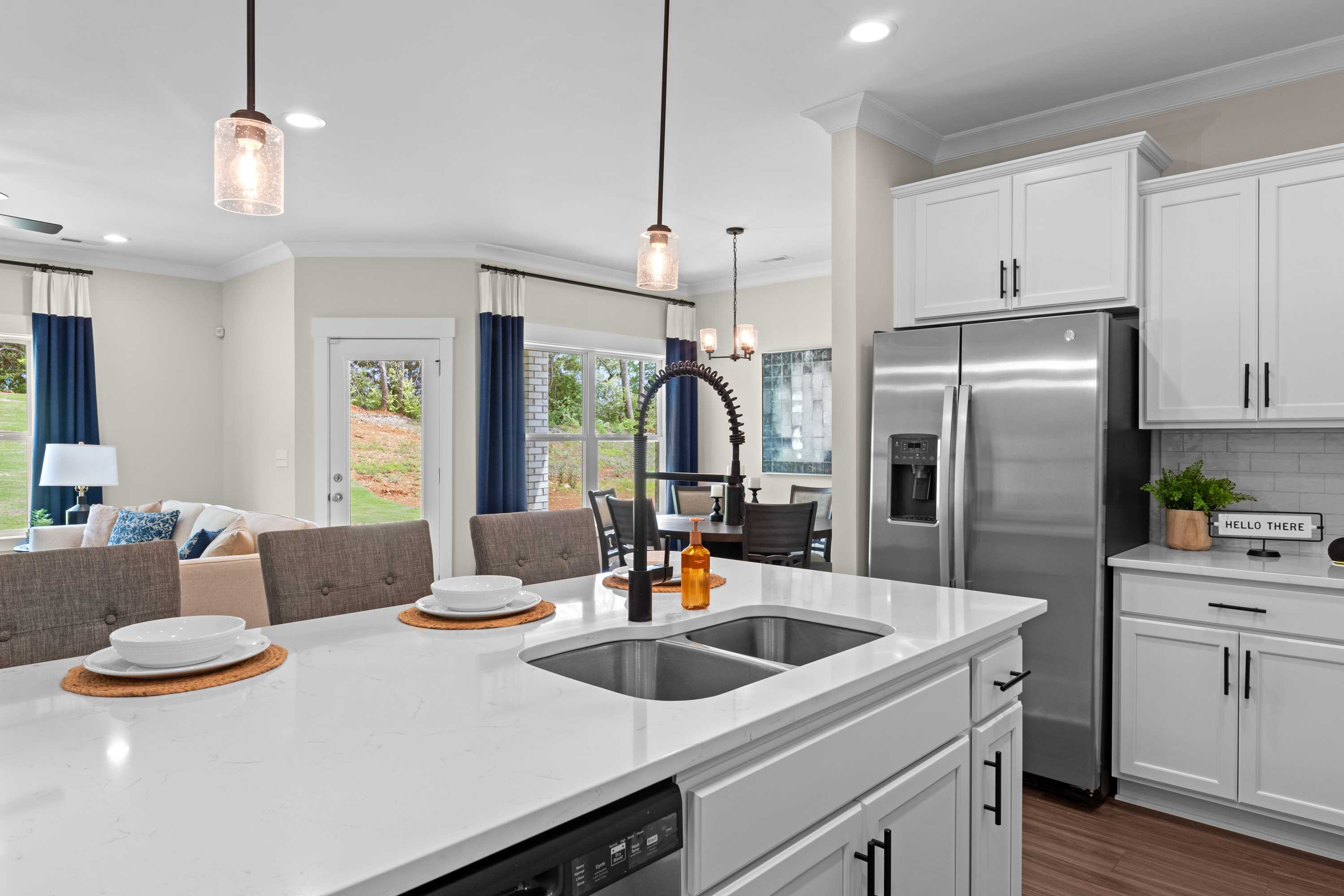 Modern kitchen in Ivy Hills Toney Alabama with white shaker cabinets, quartz island sink, stainless steel appliances, and hardwood floors