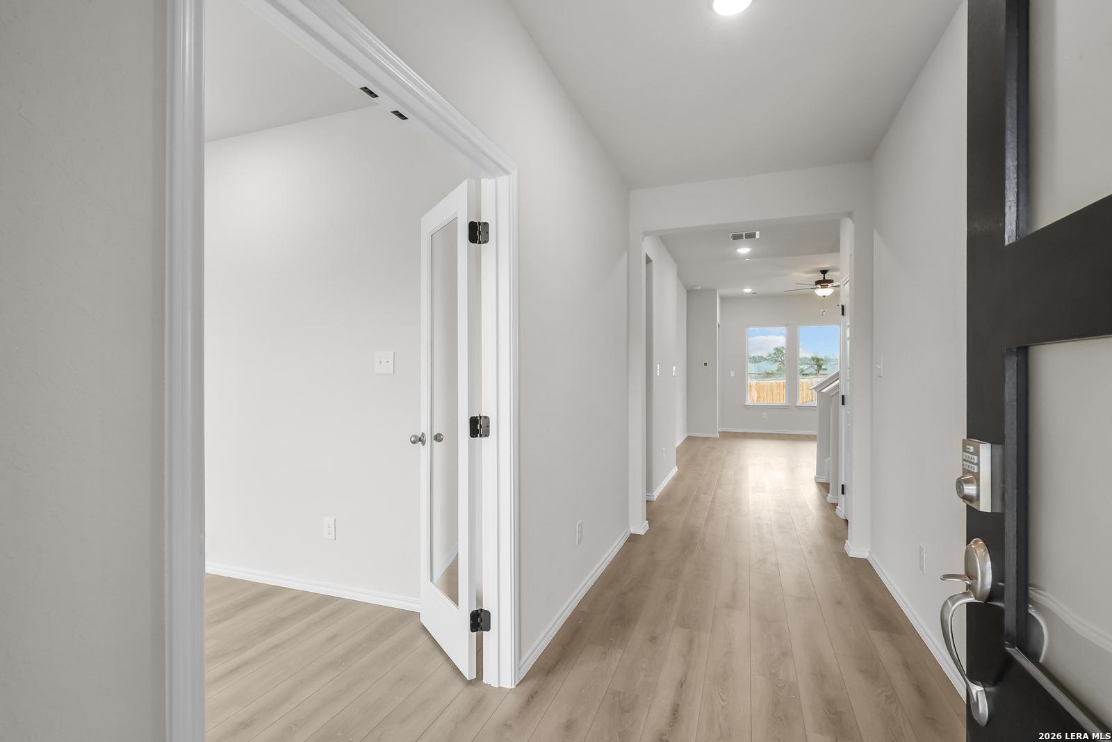 Bright entryway hallway with glass-paneled front door and wood flooring in Davidson Homes The Sequoia A, San Antonio