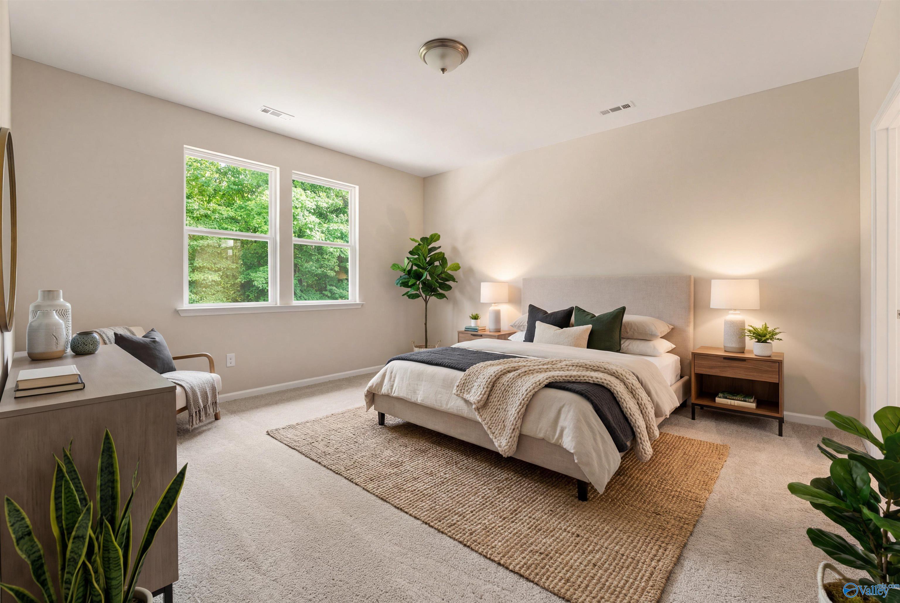 Serene master bedroom with king bed, beige walls, large windows, and potted plants in Davidson Homes The Phoenix, Fayetteville, TN