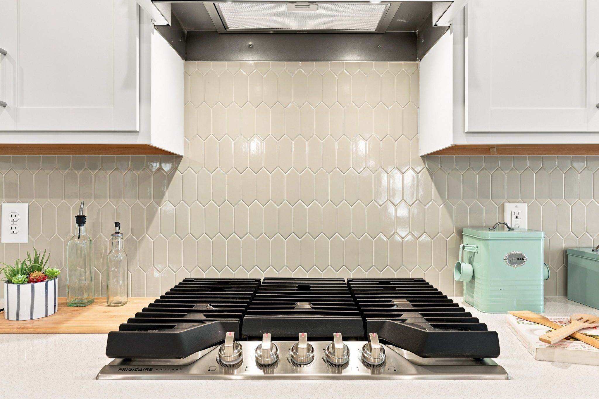 Modern kitchen cooktop in The Jordan A featuring a stylish picket tile backsplash and stainless steel range.
