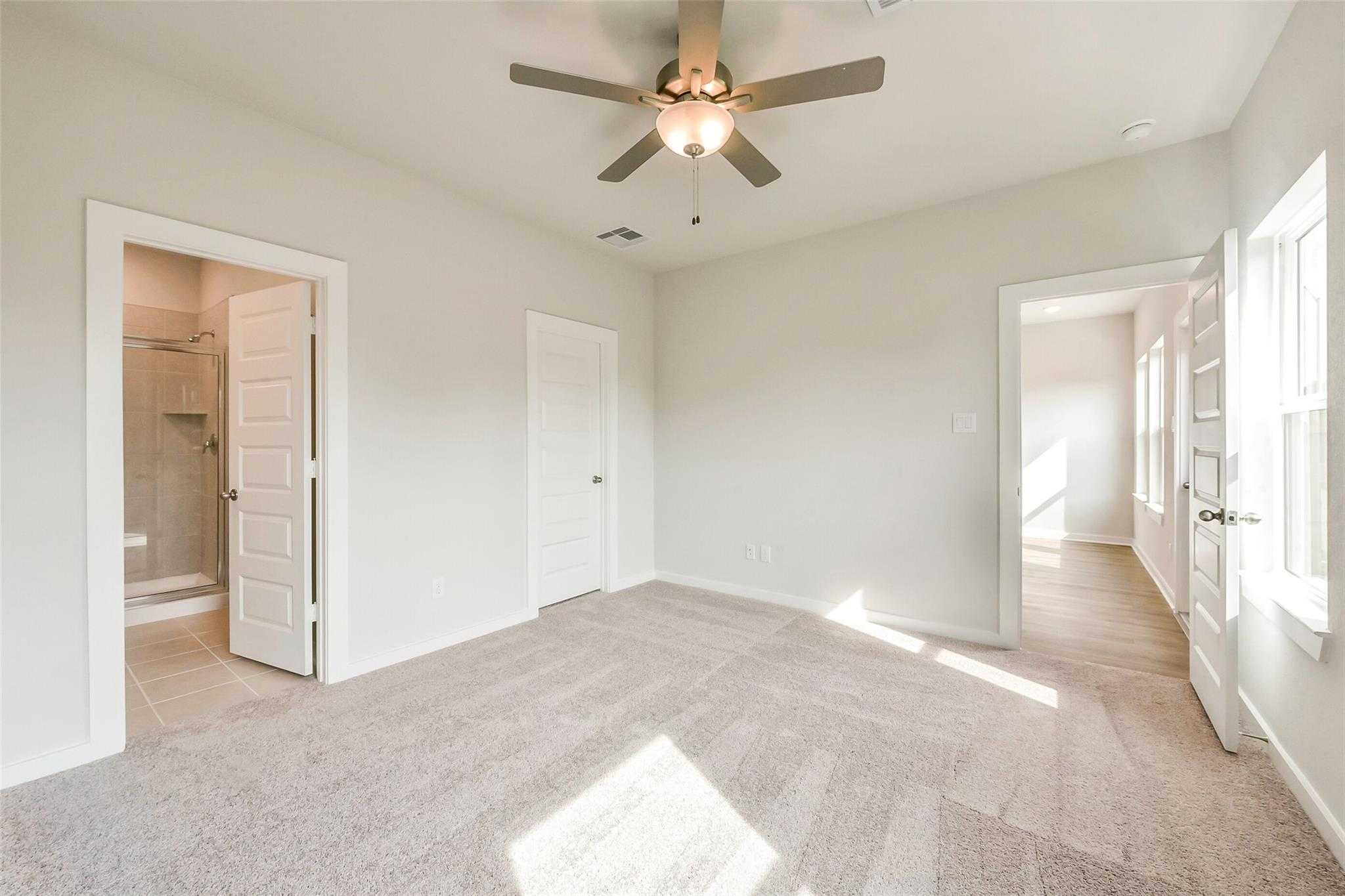 Spacious secondary bedroom with ceiling fan, en-suite bath, and walk-in closet in Davidson Homes The Comal G, Dayton, Texas