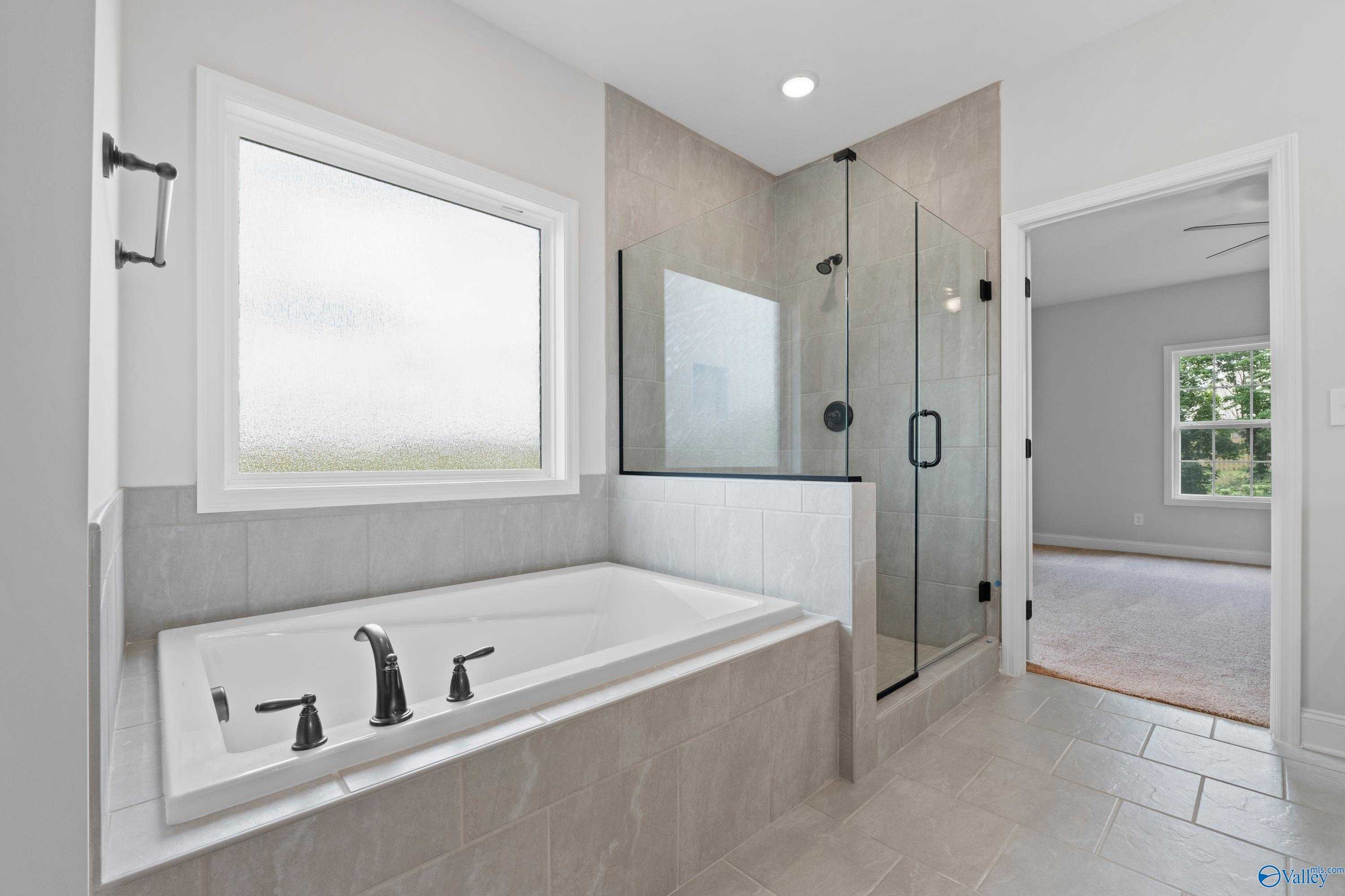 Luxurious master bathroom featuring freestanding tub and frameless glass shower in Davidson Homes The Kirkland with Bonus, Harvest, Alabama