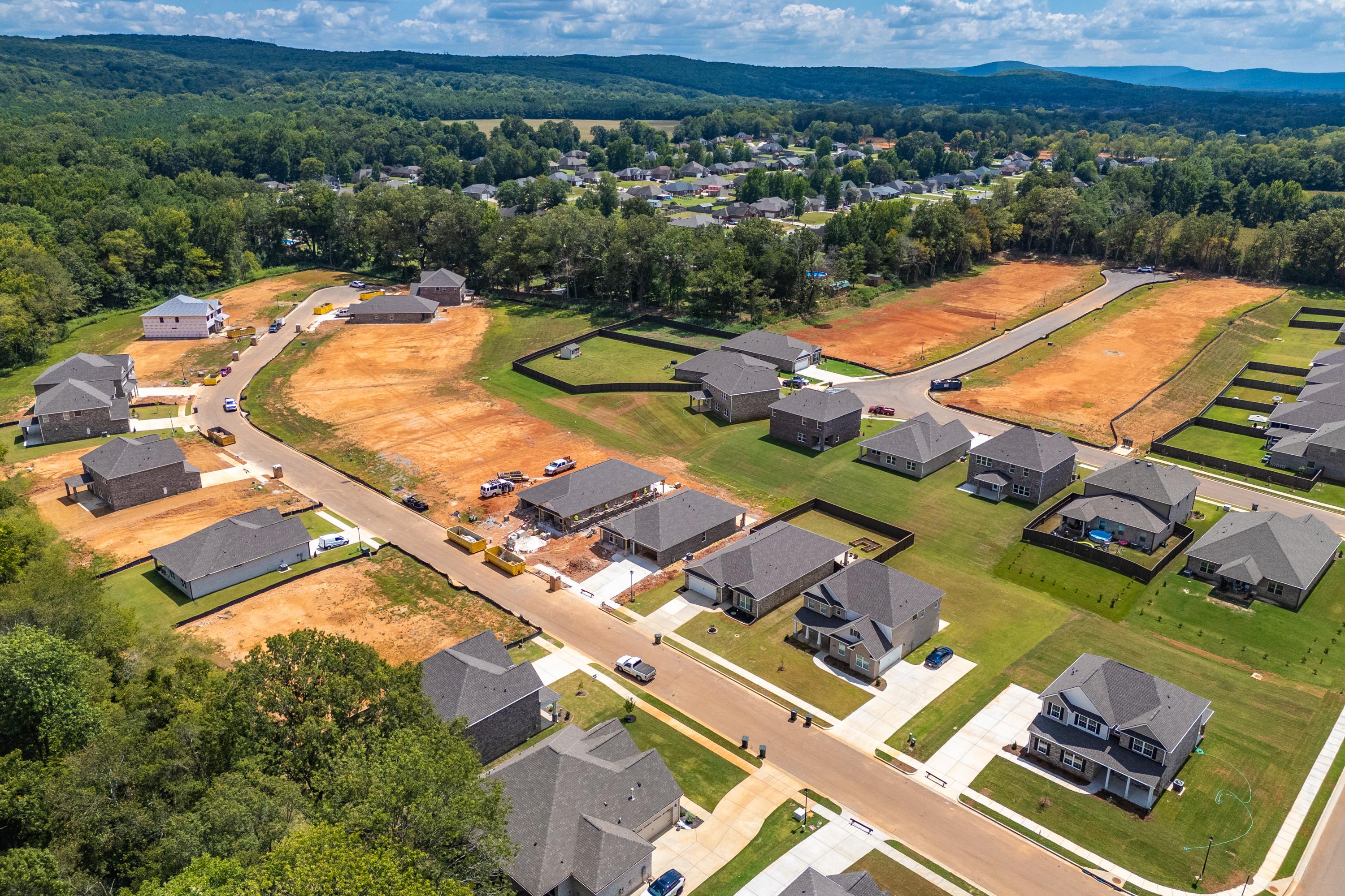 Aerial view of new homes under construction at Creek Grove in New Market, Alabama by Davidson Homes amid forested hills