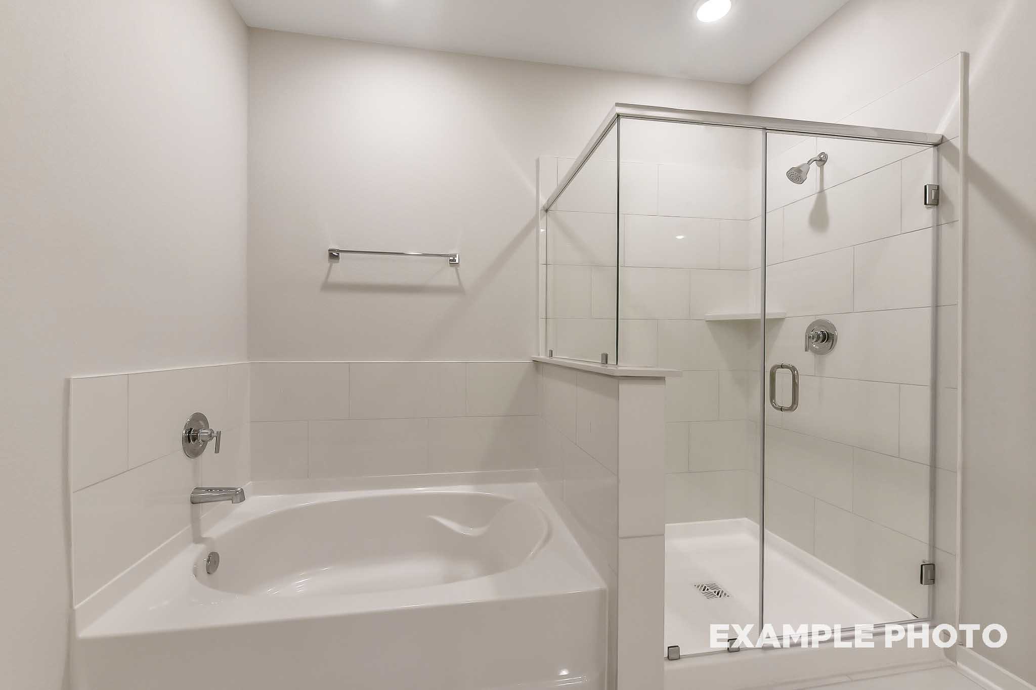 Spacious master bathroom in The Laguna B with white subway tile, soaking tub, and frameless glass shower