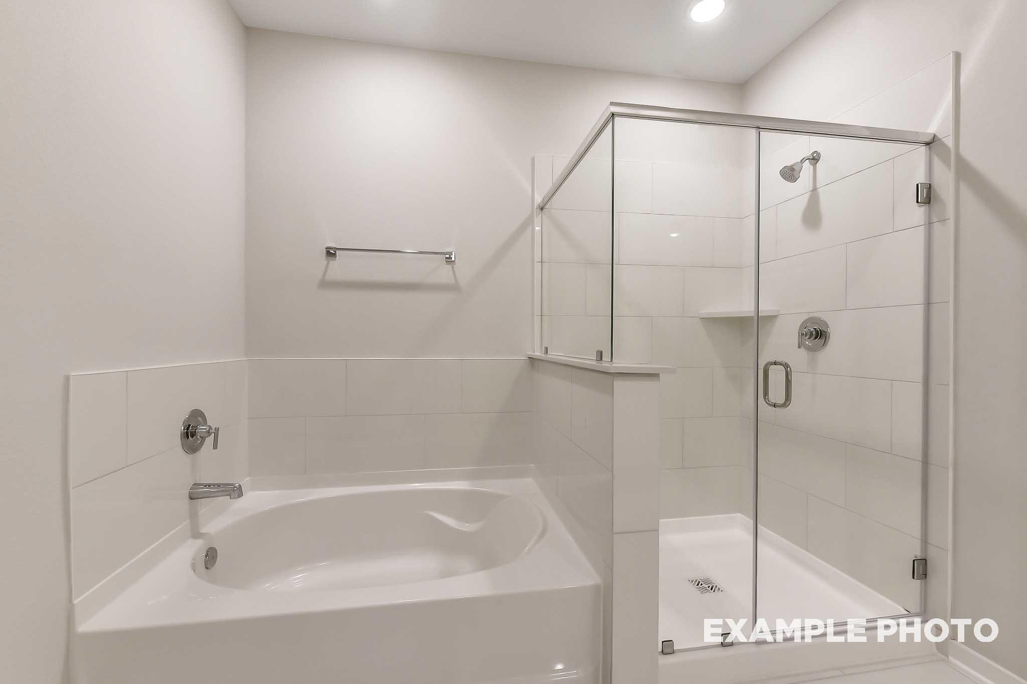Spacious master bathroom in The Laguna B with white subway tile, soaking tub, and frameless glass shower