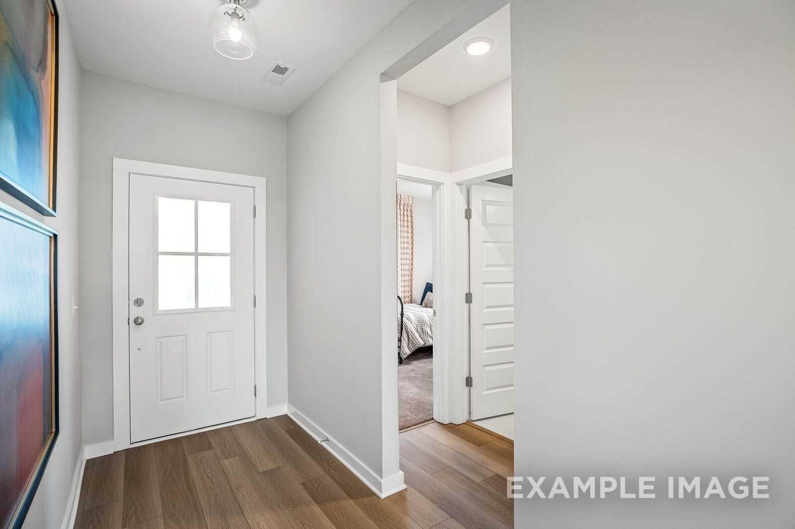 Bright entryway with white glass-paneled door, hardwood floors, and bedroom view in Davidson Homes Franklin B, White House, TN
