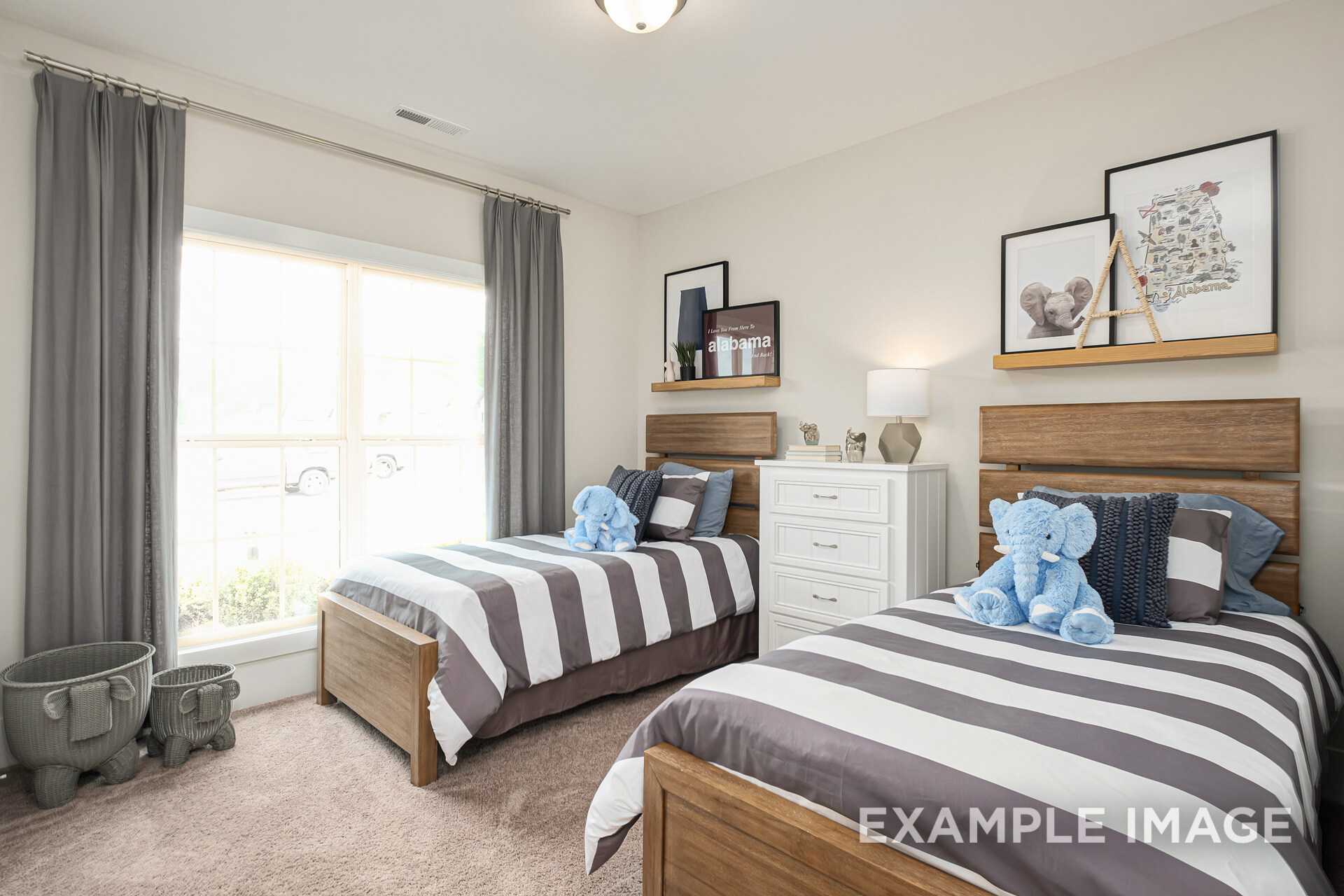 Cozy children's bedroom in The Daphne D featuring twin beds with gray striped bedding, blue elephant pillows, and wooden shelves