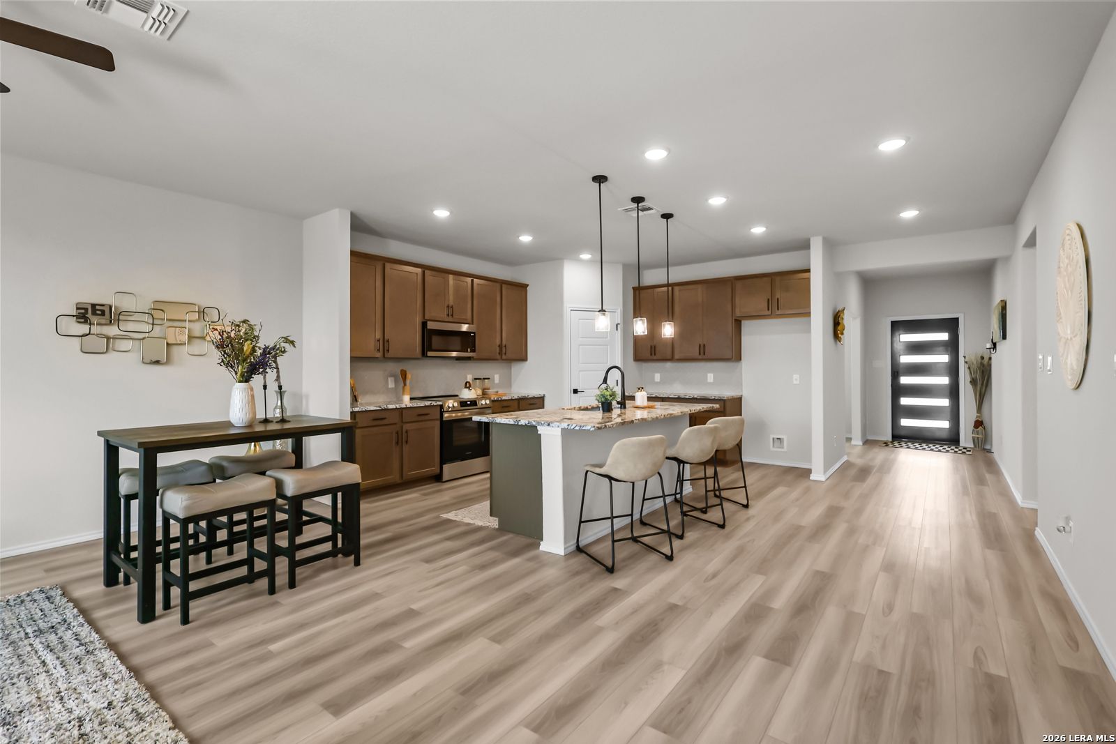 Open-concept kitchen with island, wood cabinetry, and dining area in The Douglas C floor plan at Hannah Heights, Seguin, TX.