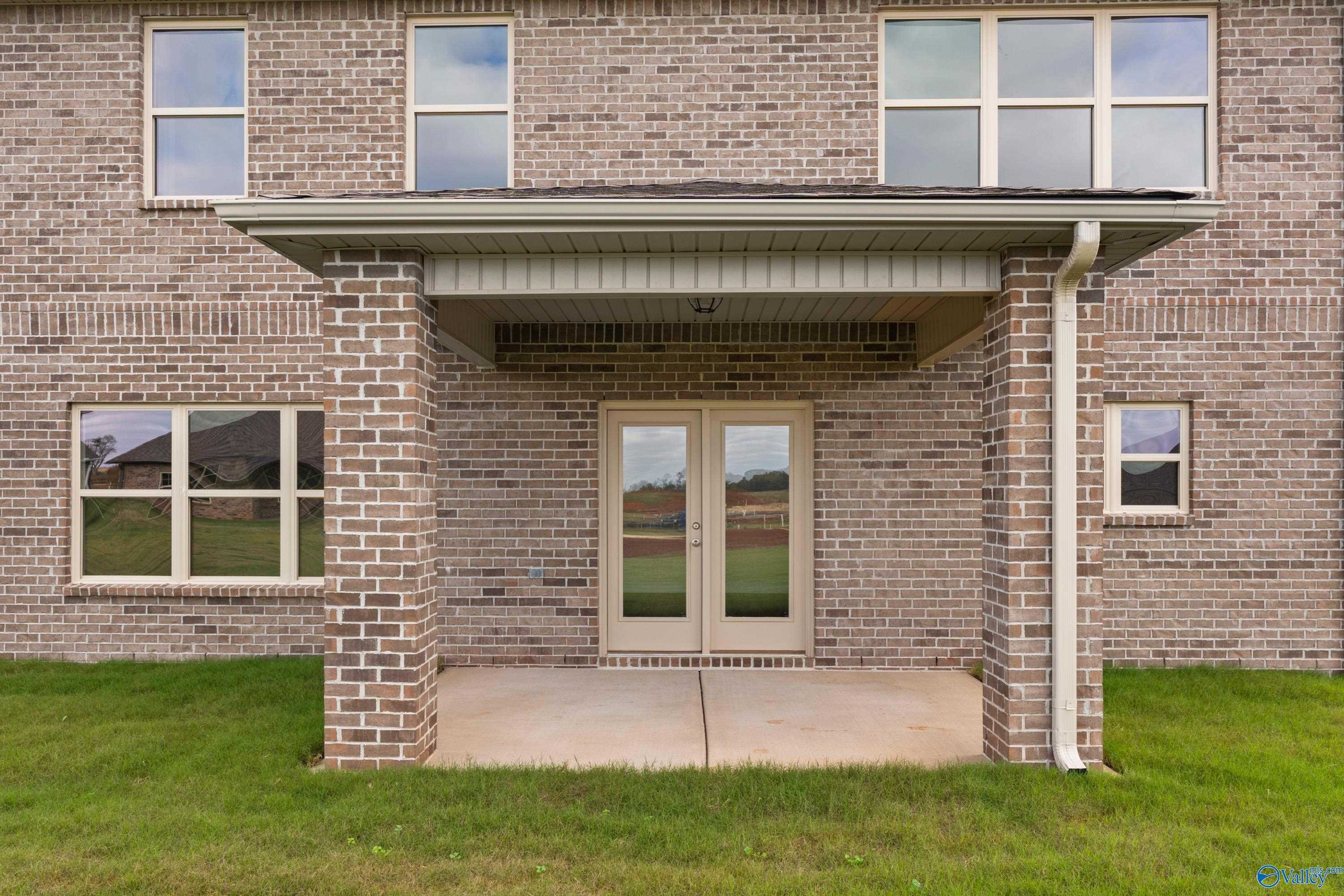 Two-story brick home with covered porch, double glass doors, and windows in Creekside, Harvest, Alabama - Davidson Homes Chelsea C
