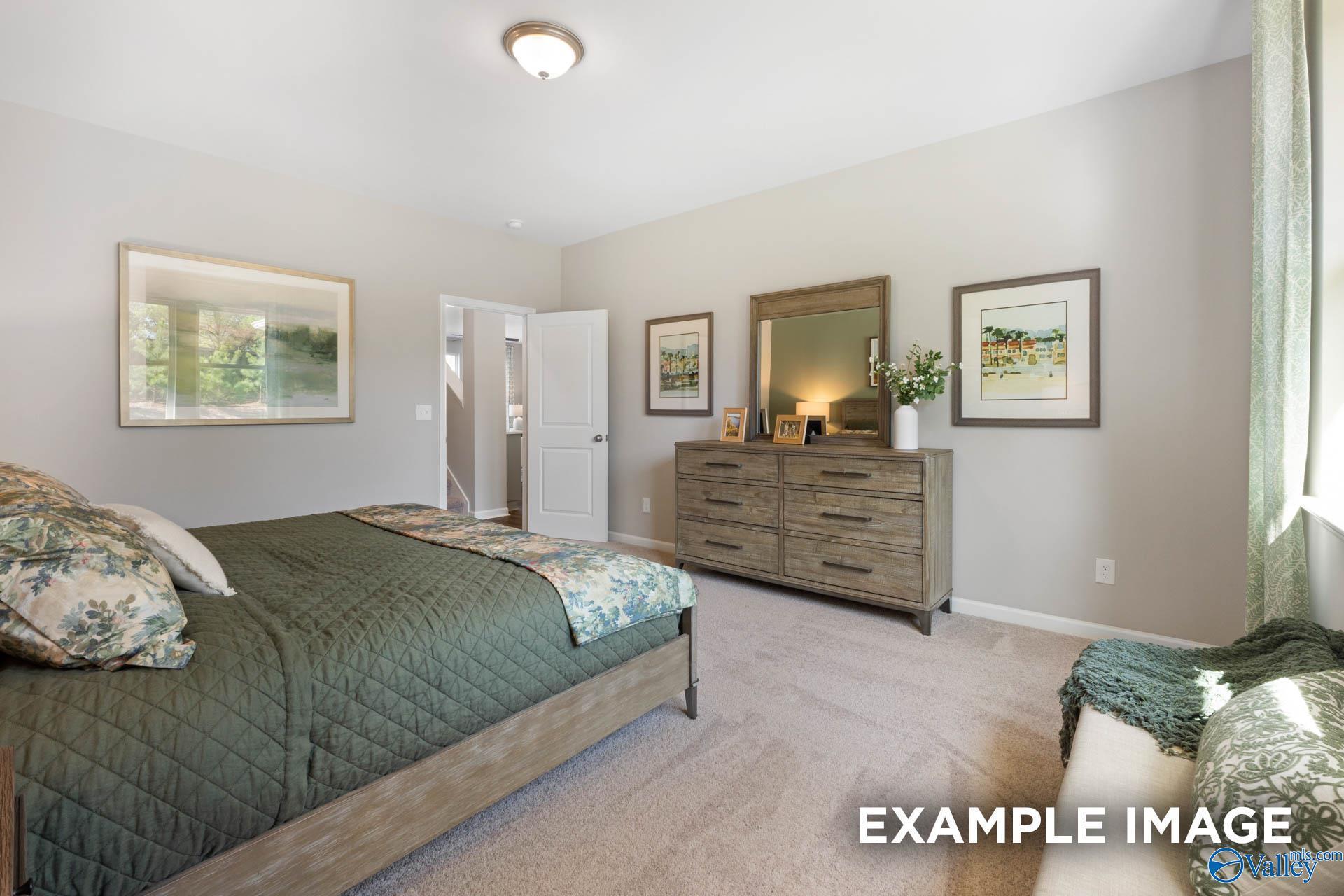 Cozy master bedroom with green quilted bed, wooden dresser, and framed landscapes in Davidson Homes The Stella, Madison, Alabama