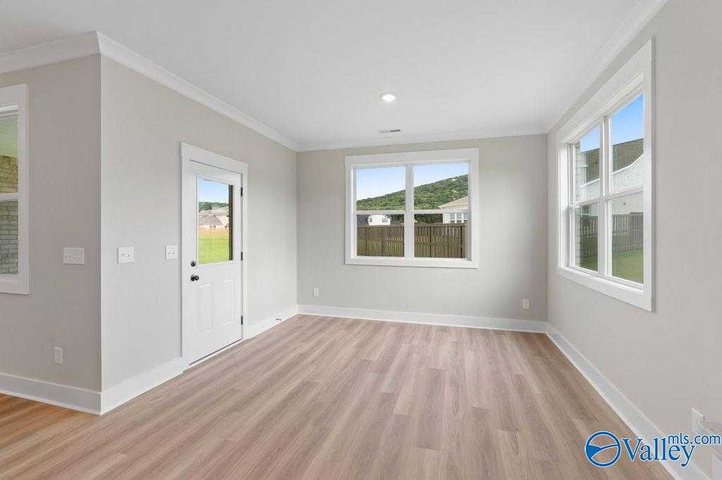 Bright living room with large windows, hardwood floors, and neutral walls in Evermore Homes The Oxford, Owens Cross Roads, Alabama