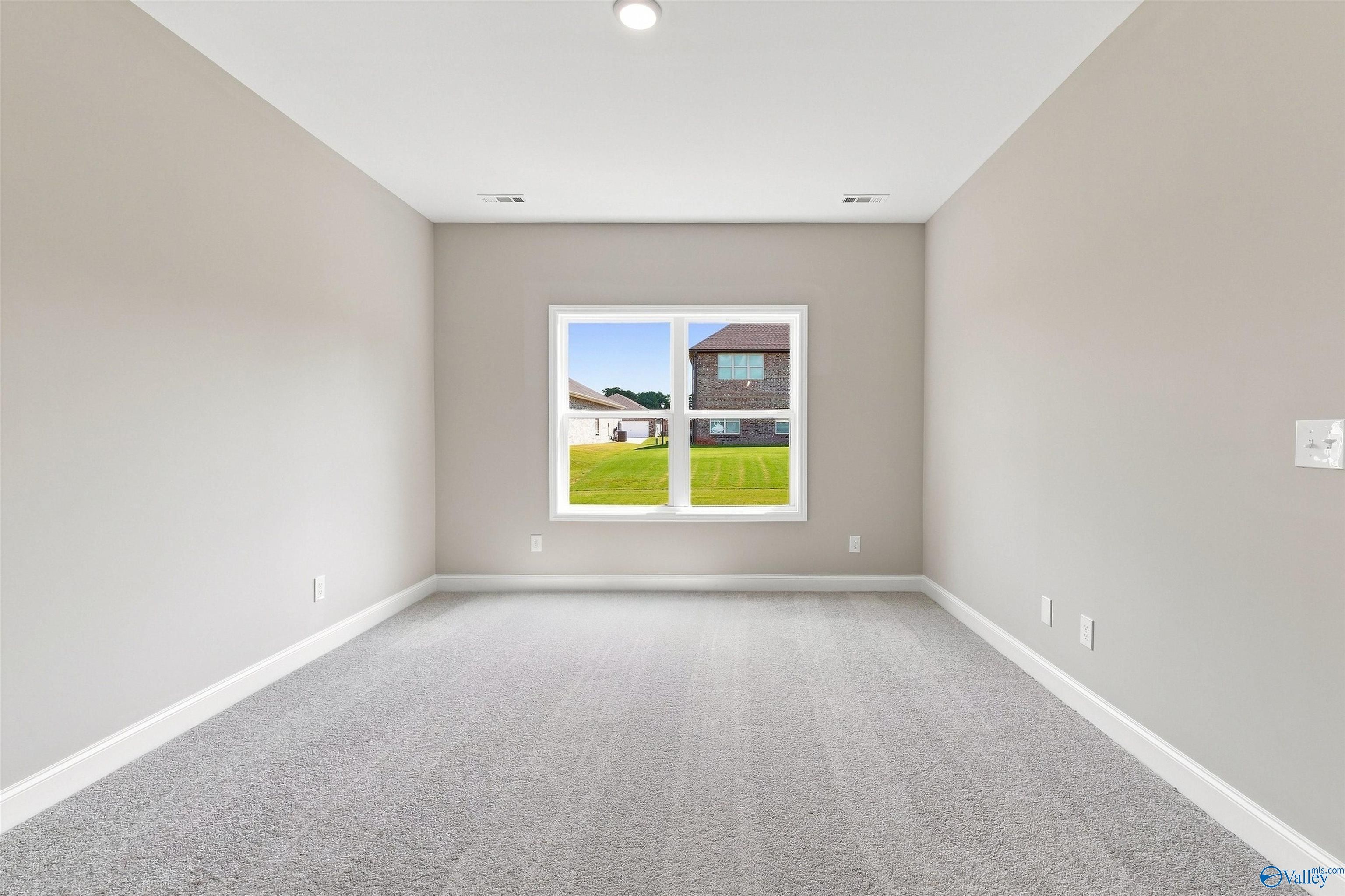 Bright neutral bedroom with plush gray carpet and window view in Davidson Homes The Franklin C, Wood Trail, Toney, Alabama