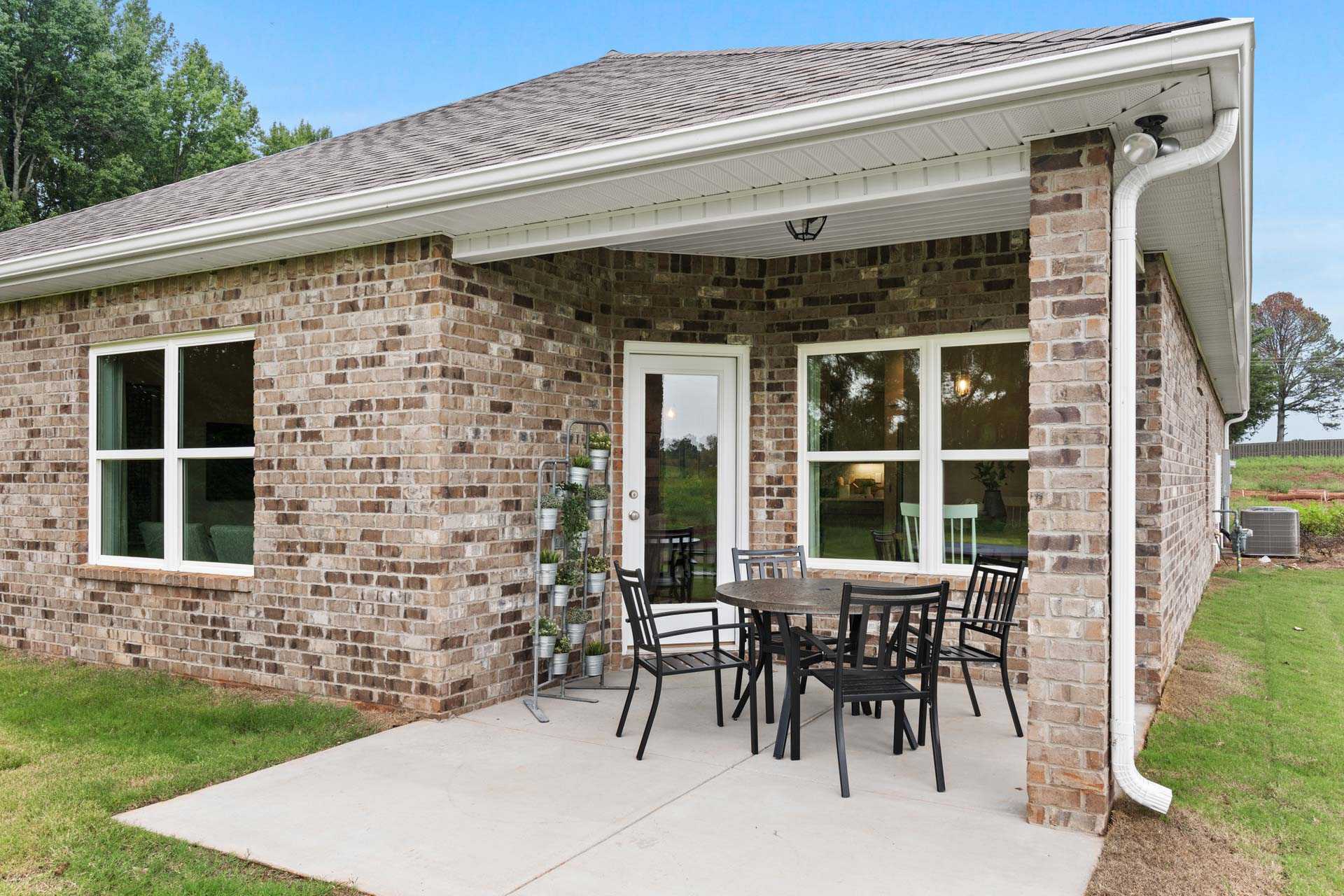 Covered patio with brick home exterior and black metal dining set at The Meadows in Athens, Alabama