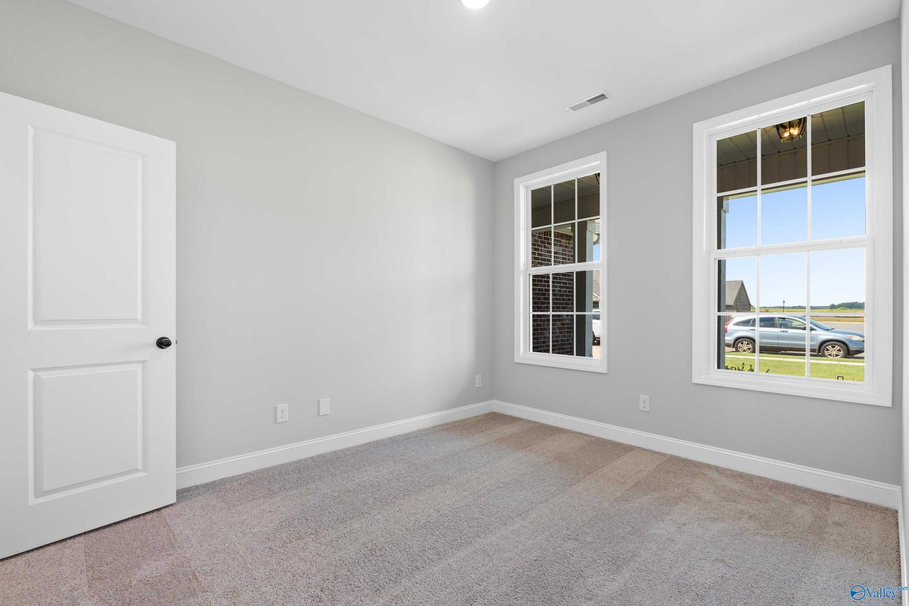 Bright secondary bedroom featuring gray walls, double windows with rural view, and plush carpet in Davidson Homes The Rockford, Toney, AL