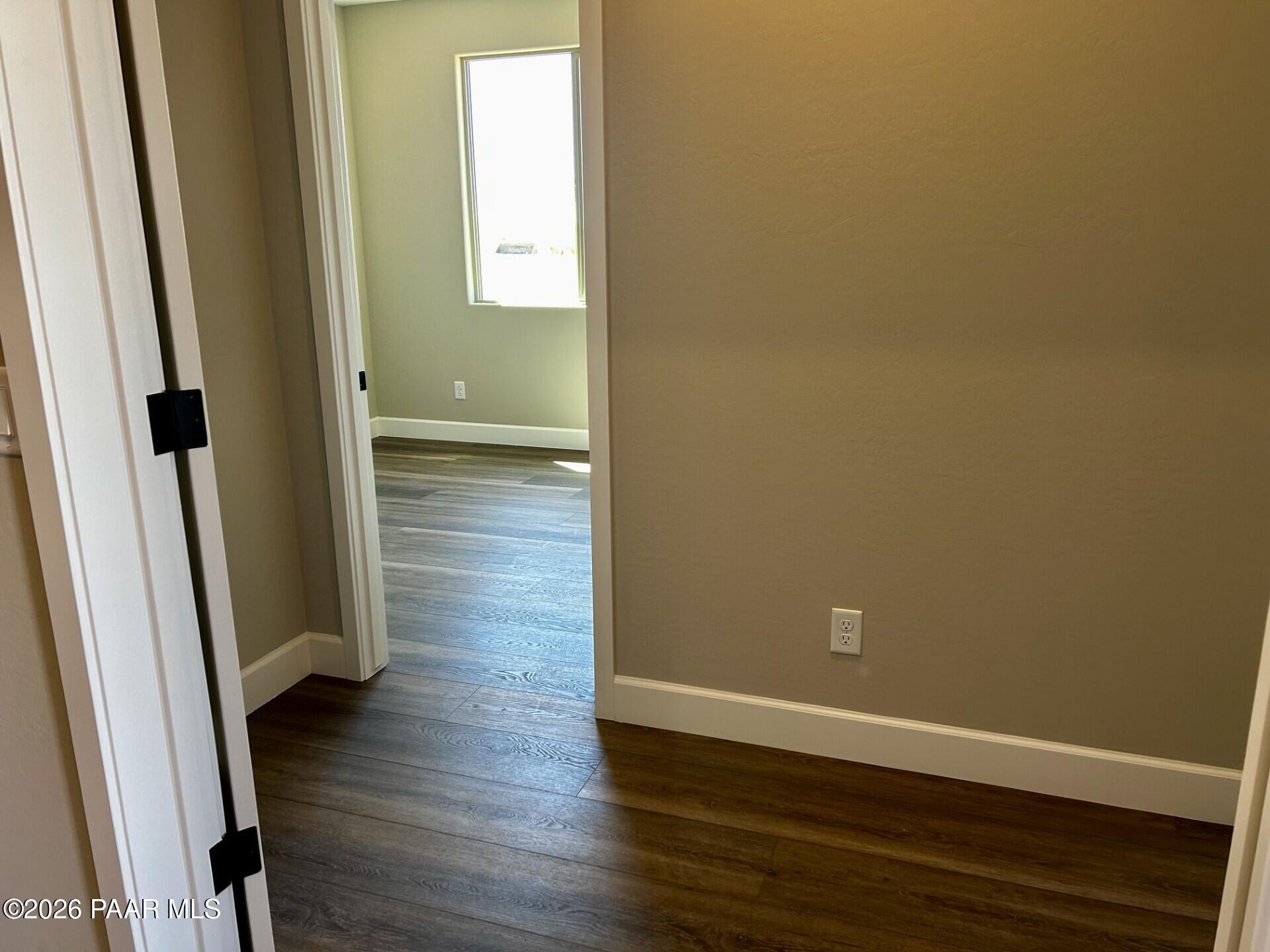 Bright hallway with tan walls, luxury vinyl plank flooring, and sunlit window in Davidson Homes The Harmony C, Prescott Valley, AZ