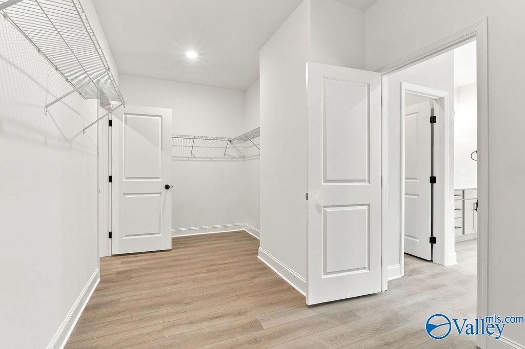 Spacious walk-in closet with wire shelving and luxury vinyl plank flooring in Davidson Homes' The Rockford, Hartselle, Alabama.