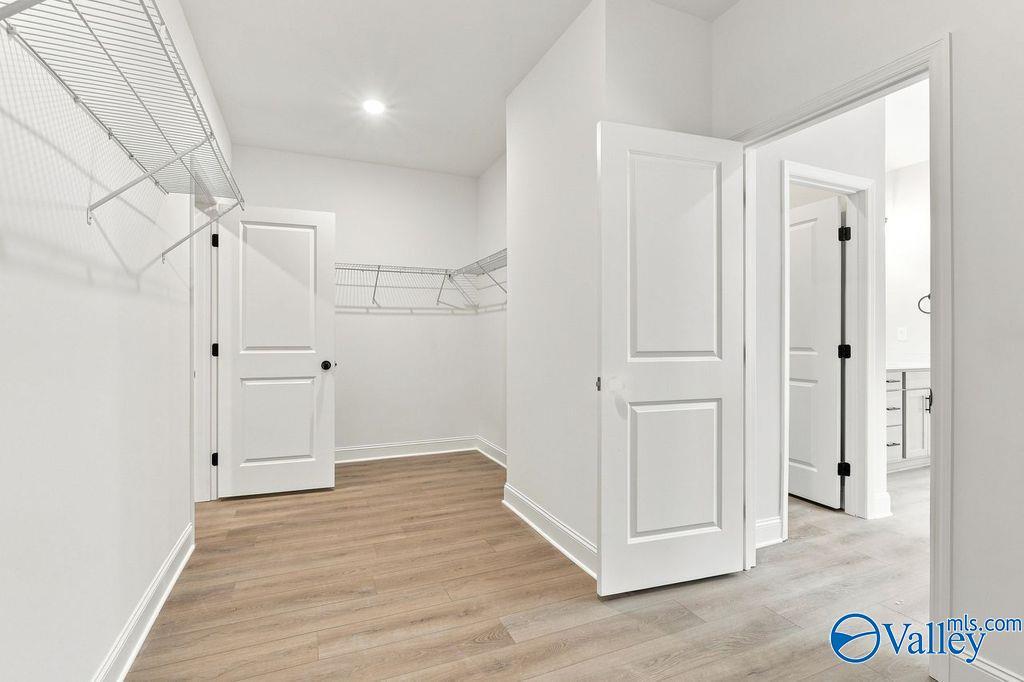 Spacious walk-in closet with wire shelving and luxury vinyl plank flooring in Davidson Homes' The Rockford, Hartselle, Alabama.