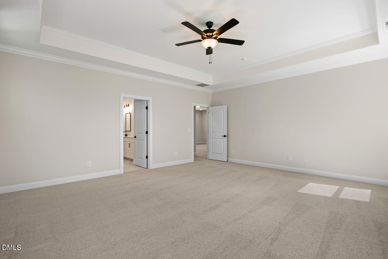 Spacious carpeted master bedroom with tray ceiling and ceiling fan in Davidson Homes Crawford D plan, Rockport, Wake Forest, NC