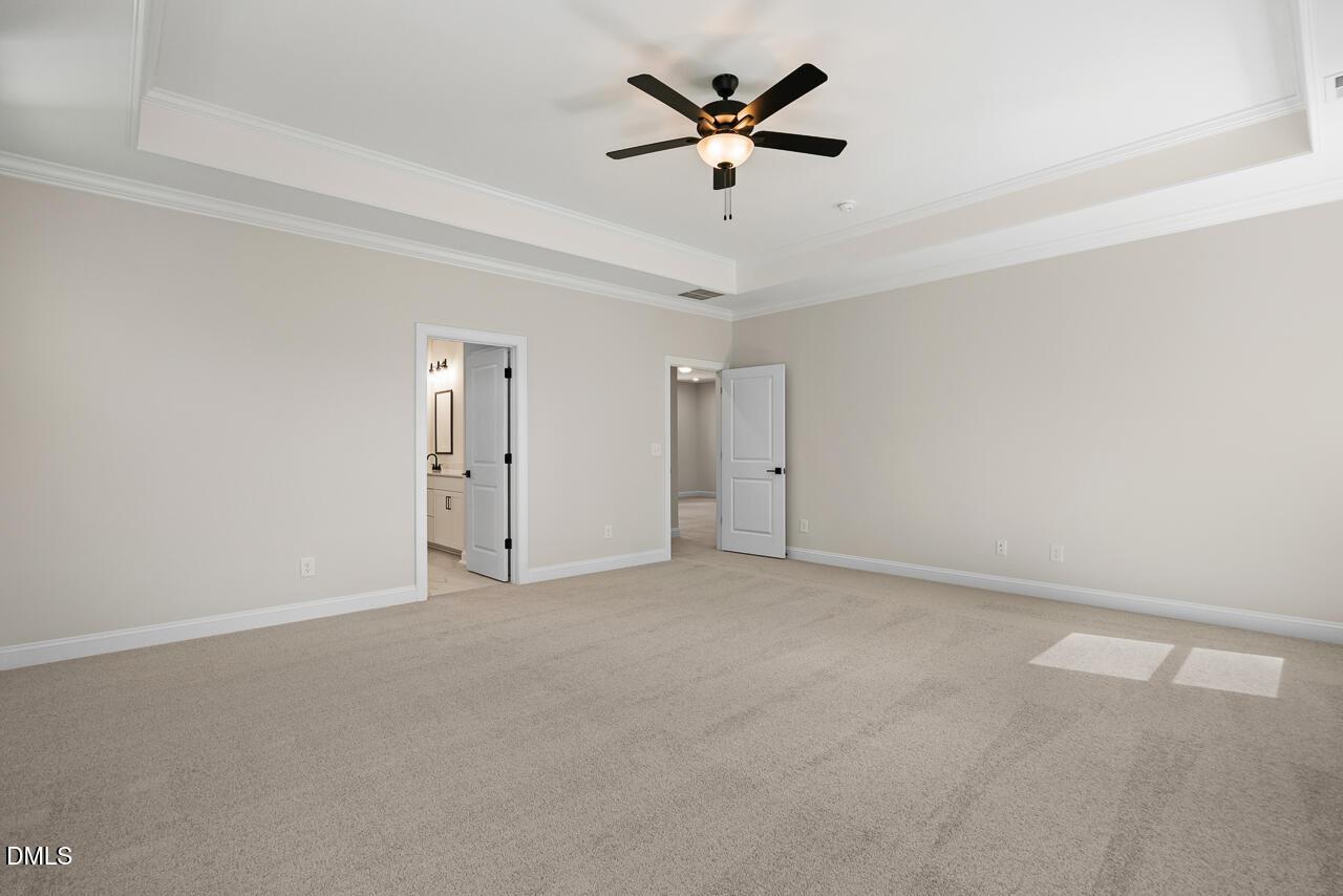 Spacious carpeted master bedroom with tray ceiling and ceiling fan in Davidson Homes Crawford D plan, Rockport, Wake Forest, NC