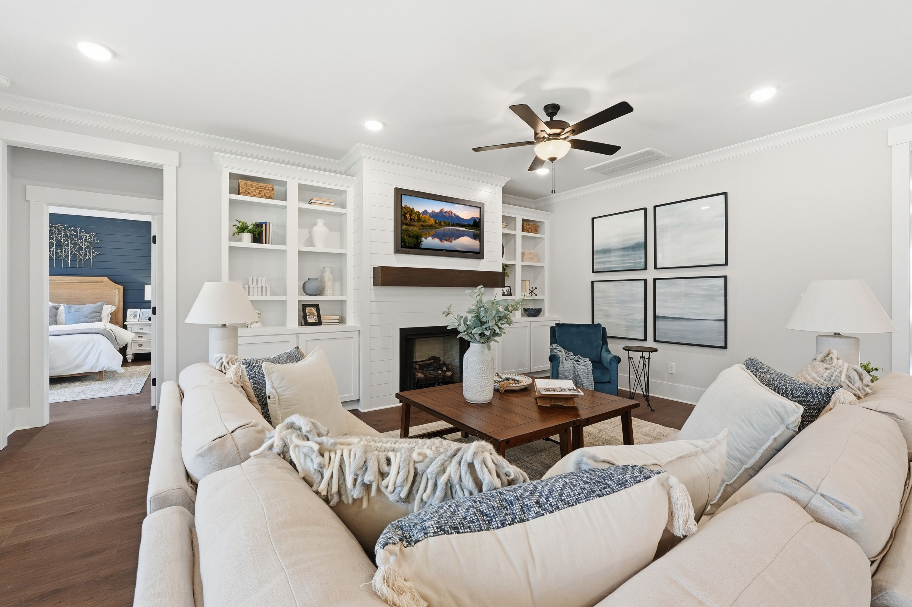 Spacious living room at Noble Ridge in Cullman Alabama with cream sectional sofa, fireplace, TV, hardwood floors, and bedroom view