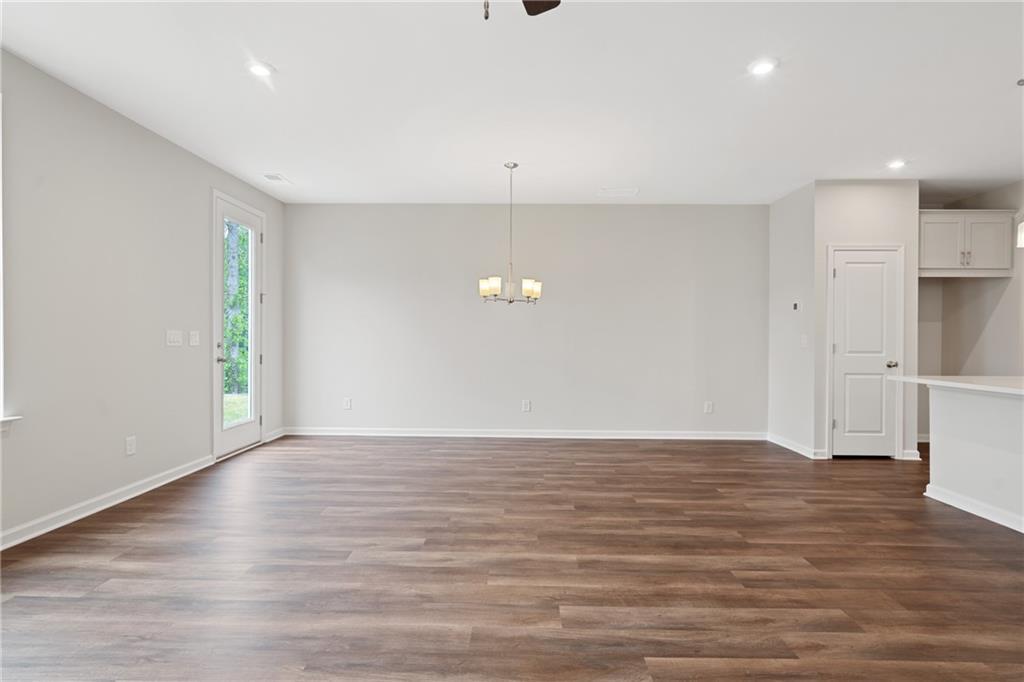 Open living-dining area with hardwood floors, ceiling fan, chandelier, and French doors in Davidson Homes The Cary B, Kennesaw, GA