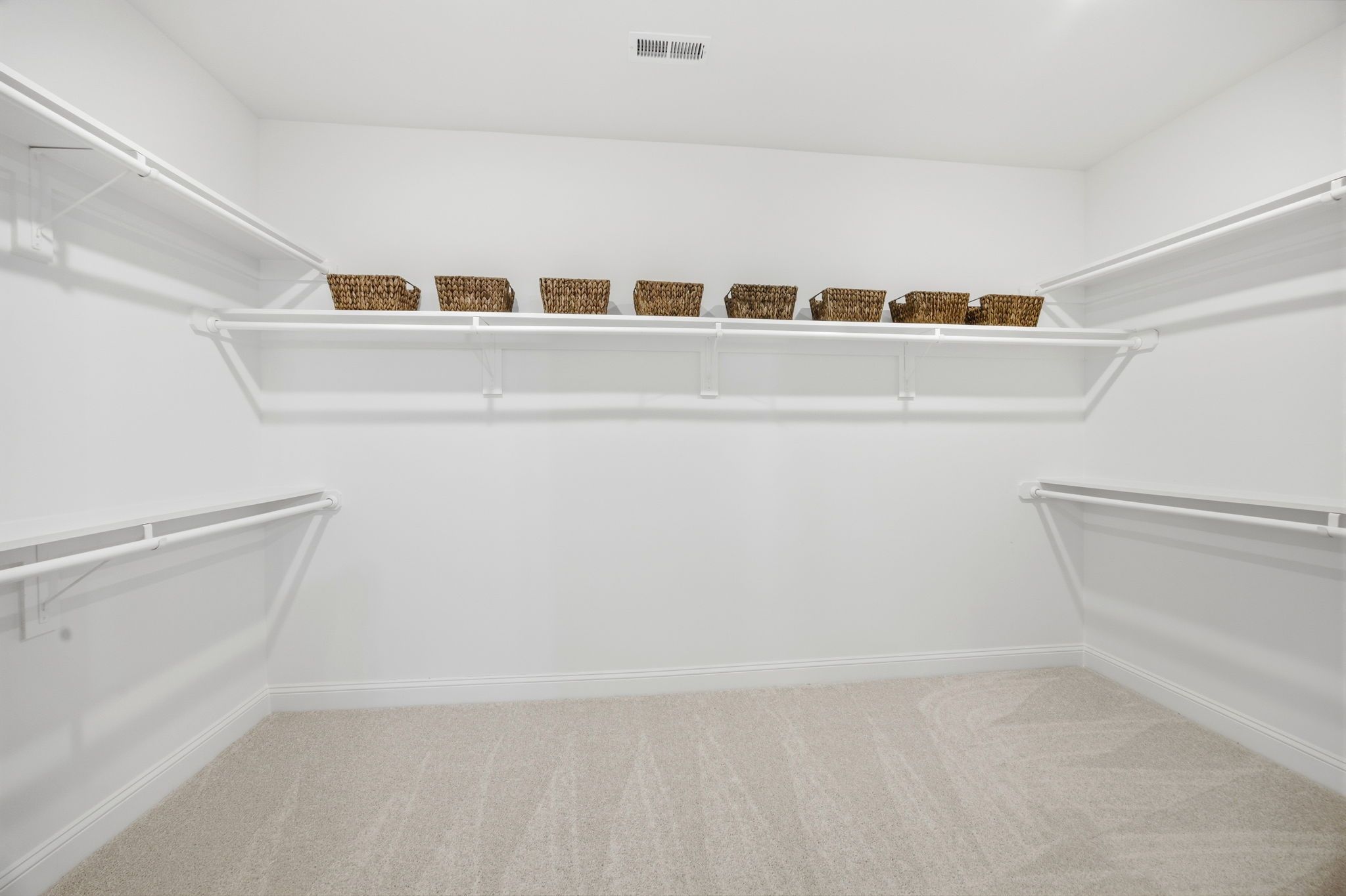 Spacious walk-in closet with white shelving and organized storage baskets at Enclave at Belmont by Davidson Homes.