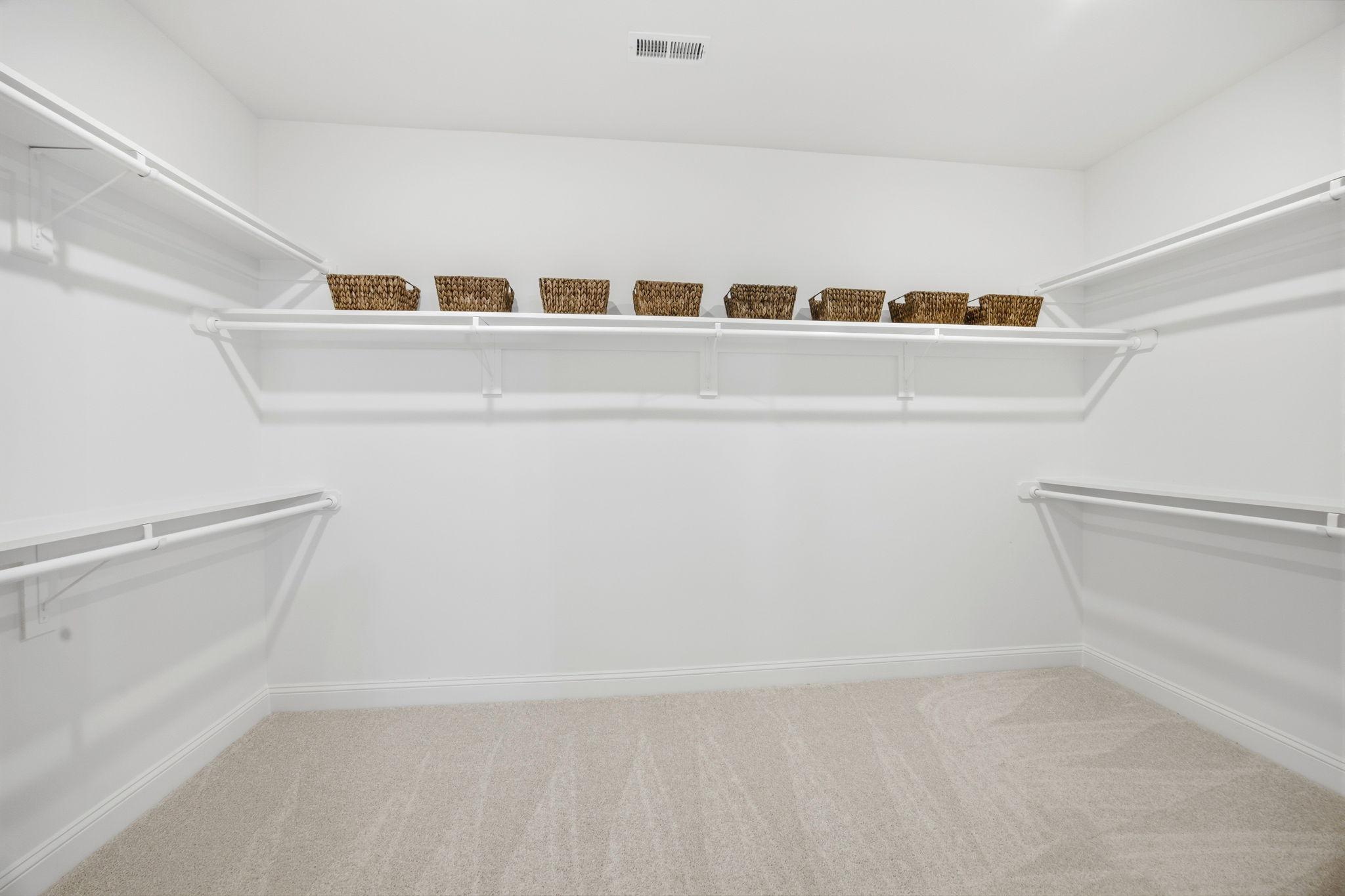 Spacious walk-in closet with white shelving and organized storage baskets at Enclave at Belmont by Davidson Homes.