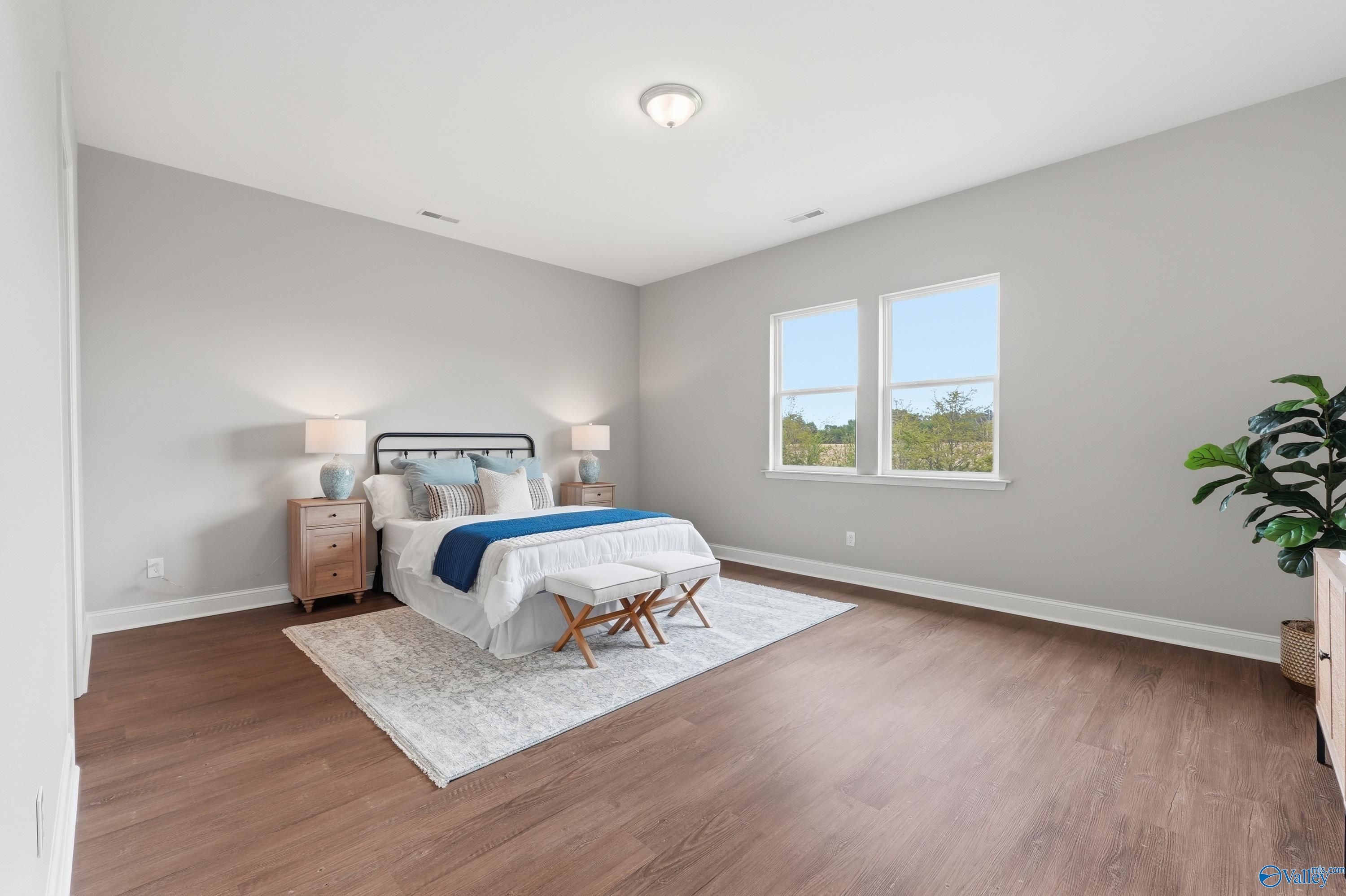 Serene bedroom with gray walls, metal-frame bed, hardwood floors, and large windows in Davidson Homes The Arcadia B, Huntsville, AL