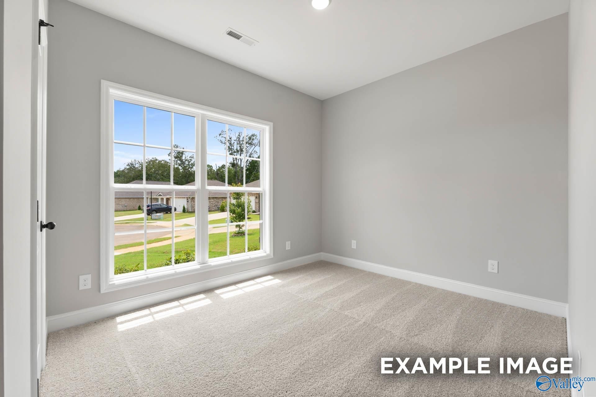 Bright empty bedroom with large window overlooking suburban neighborhood in The Asheville C, Hazel Green, Alabama
