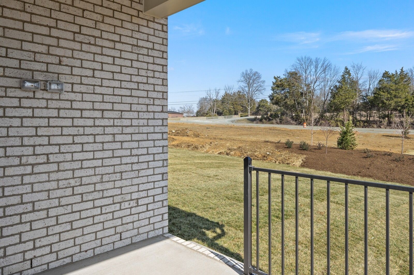 Brick home exterior with metal patio railing, lush green yard, and wooded hillside view in Benders Cove, Mt. Juliet, Tennessee