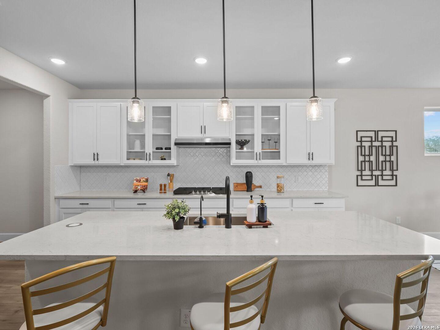 Modern kitchen with white cabinets, quartz island, and pendant lighting in a Davidson Homes Belmont floor plan, Texas.