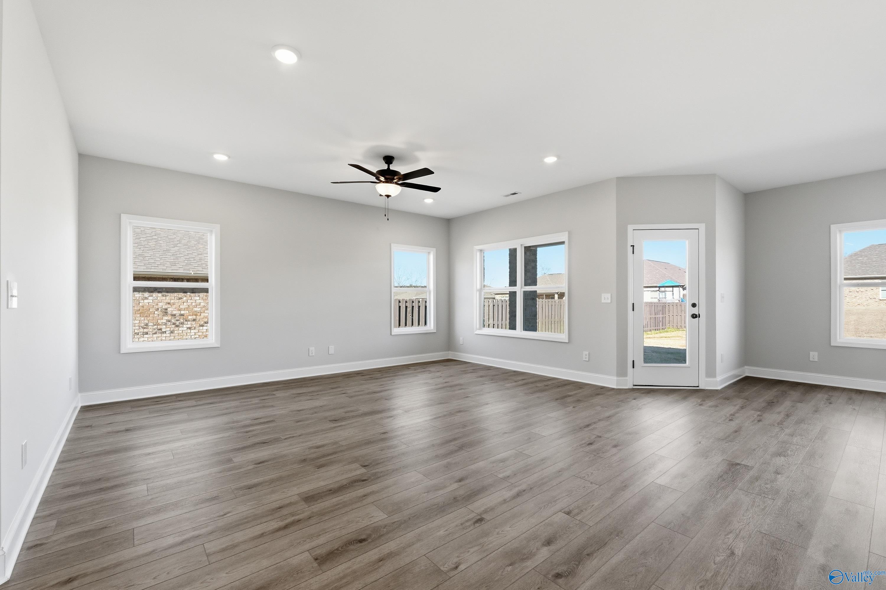 Spacious empty living room with gray walls, ceiling fan, recessed lights, and laminate flooring in Davidson Homes The Franklin C, New Market, AL