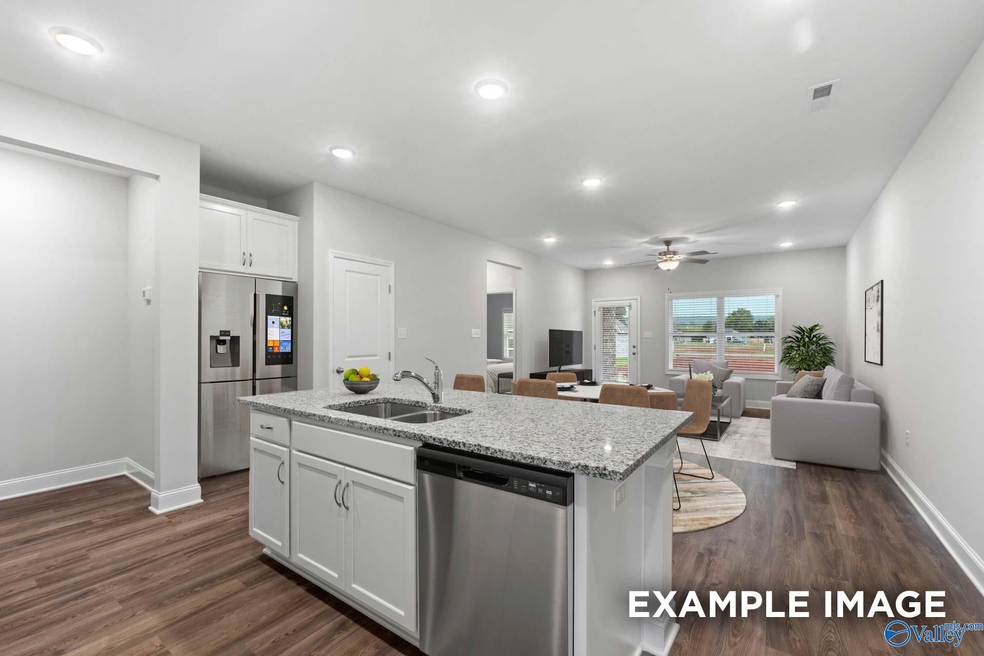 Modern open-concept kitchen with granite island, stainless appliances, and adjacent living area in Davidson Homes The Cumberland, Decatur, AL