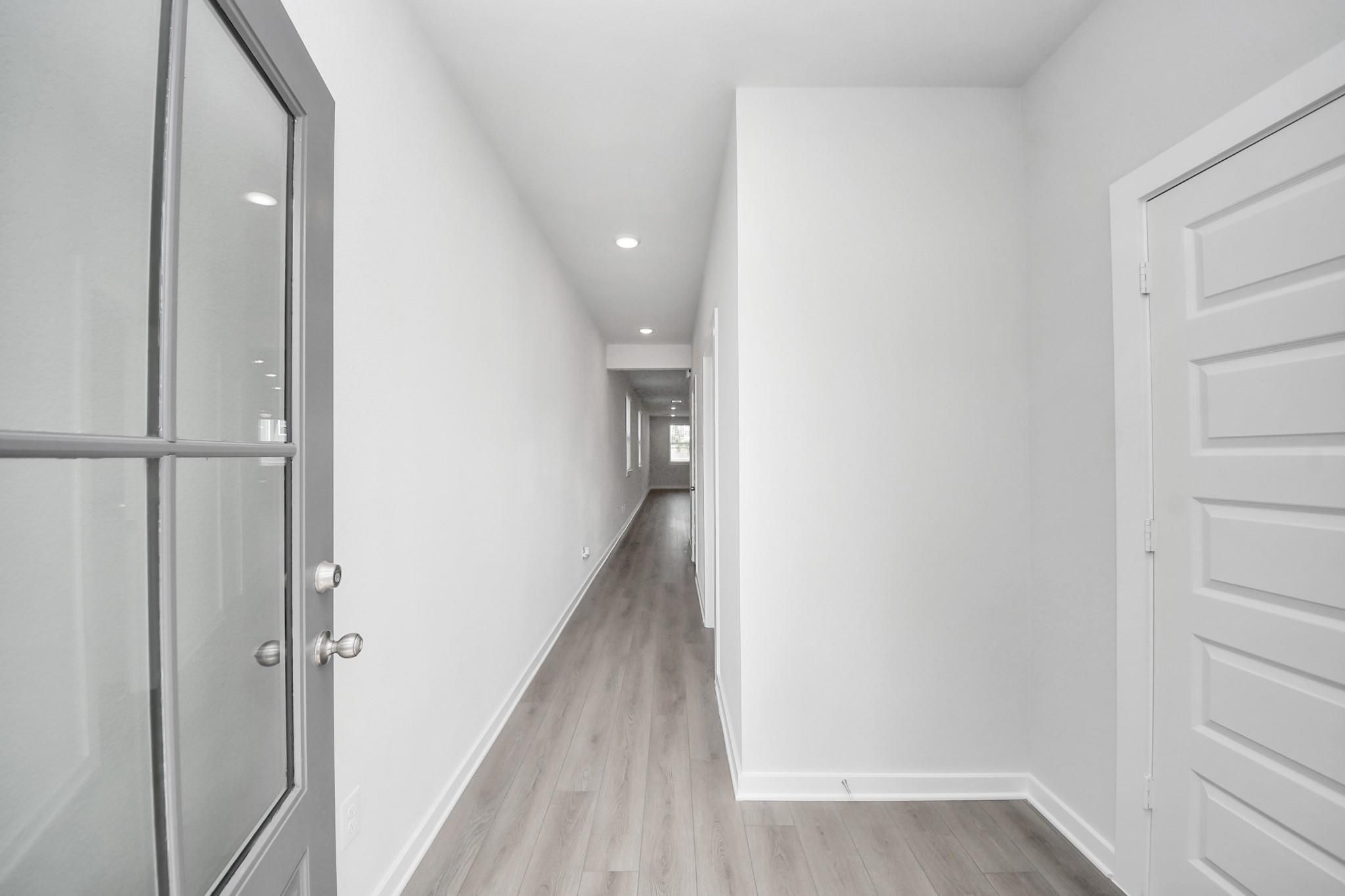 Bright, modern entryway hallway with wood-look flooring in The Frio F floor plan at Robins Landing, Houston, Texas.