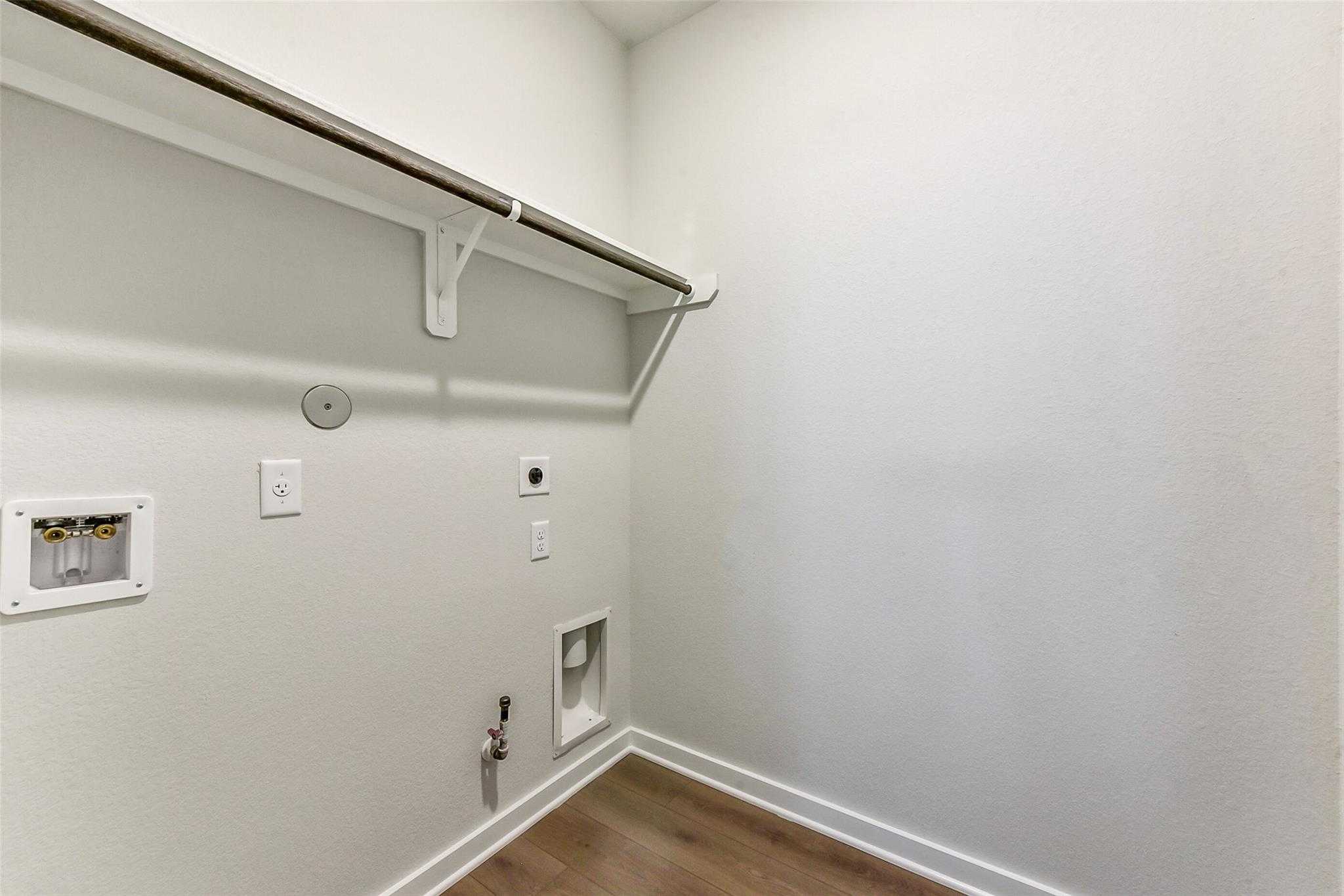 Spacious laundry room with washer/dryer hookups, hanging rod, and hardwood floors in Davidson Homes The Laguna C, Rosharon, Texas