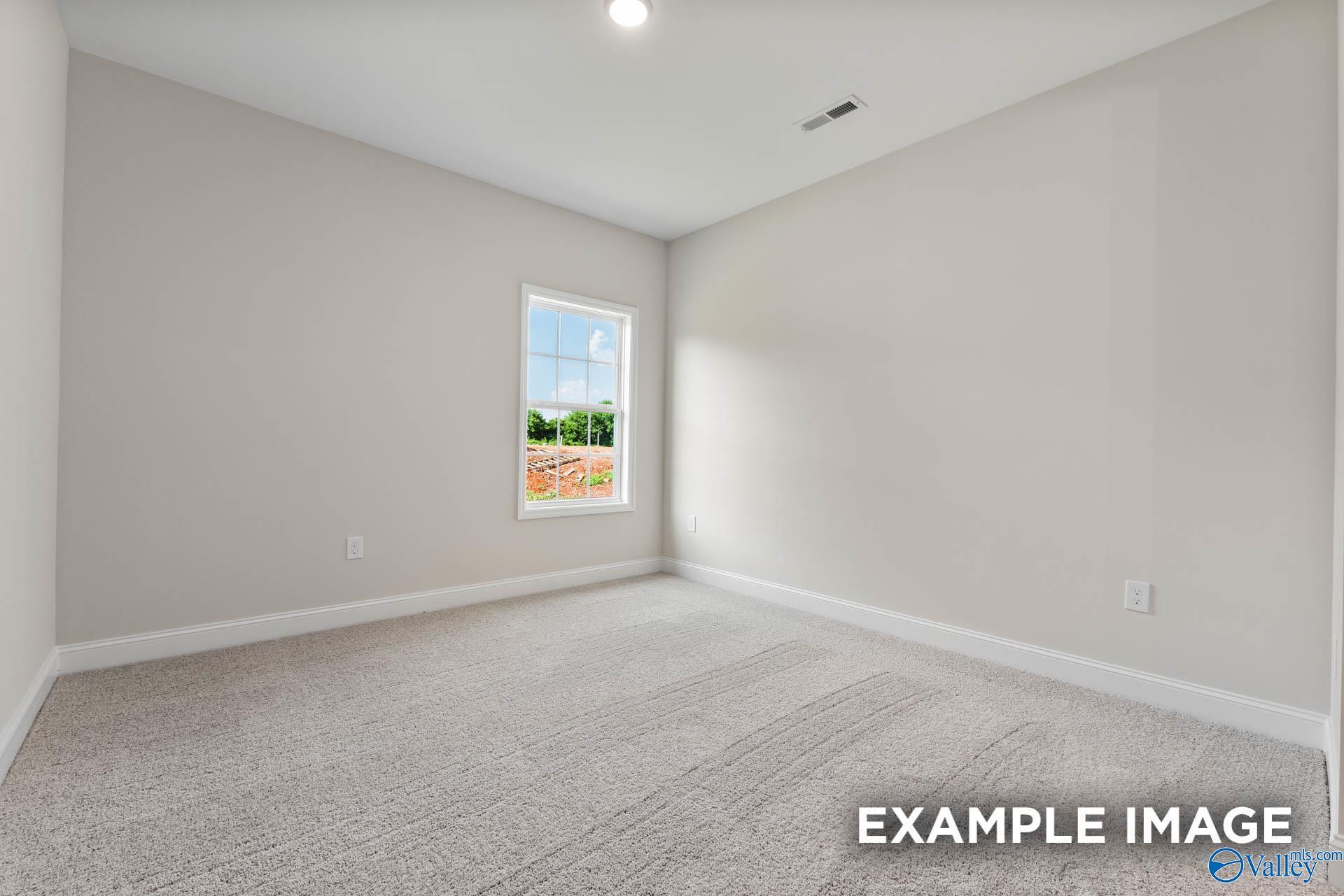 Bright secondary bedroom with light gray walls, large window overlooking greenery, and plush carpet in The Finleigh plan, Huntsville, AL