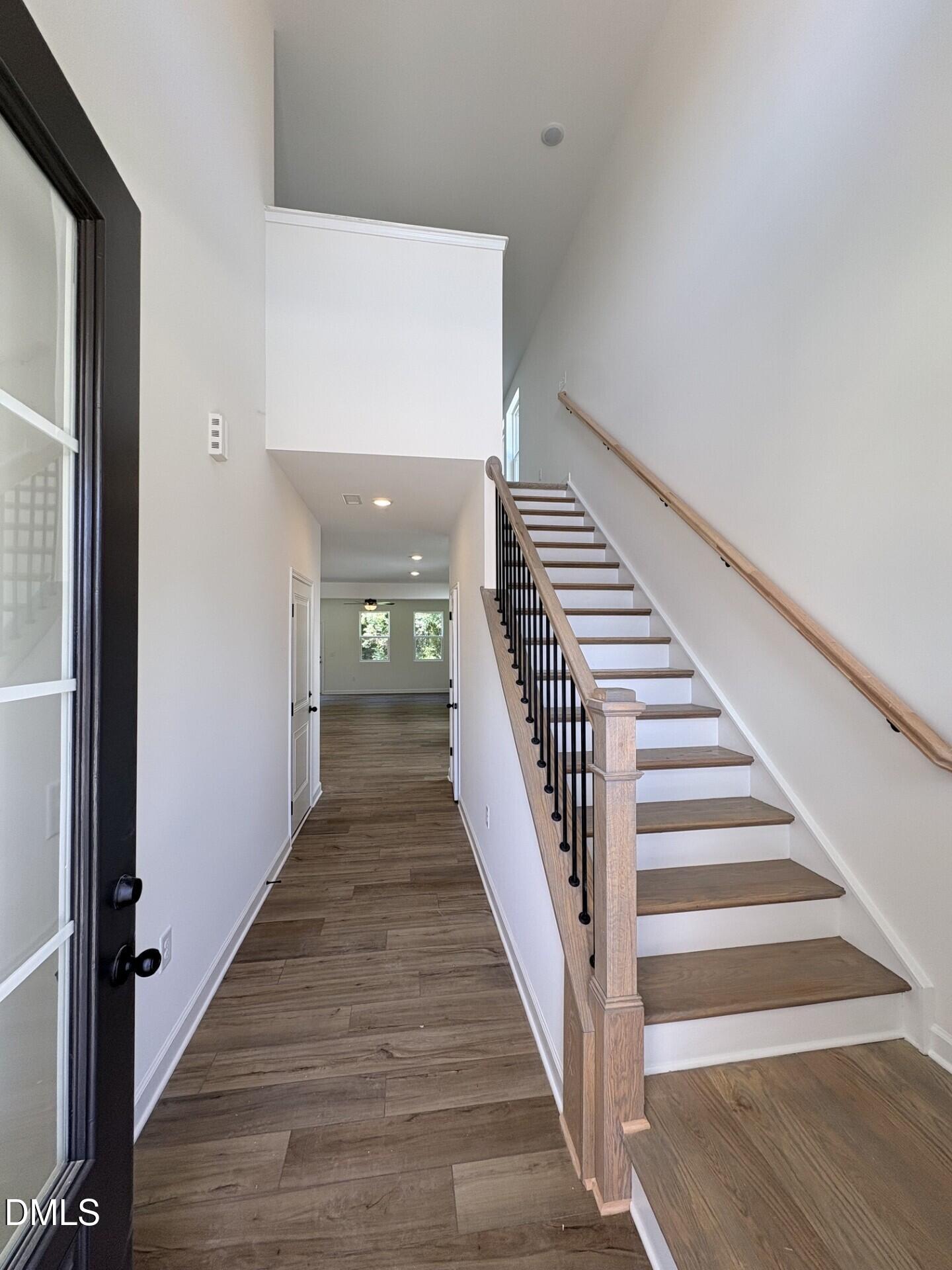 Two-story foyer with wood-look tile flooring, oak staircase, and black front door in Davidson Homes Adalynn A, Zebulon NC