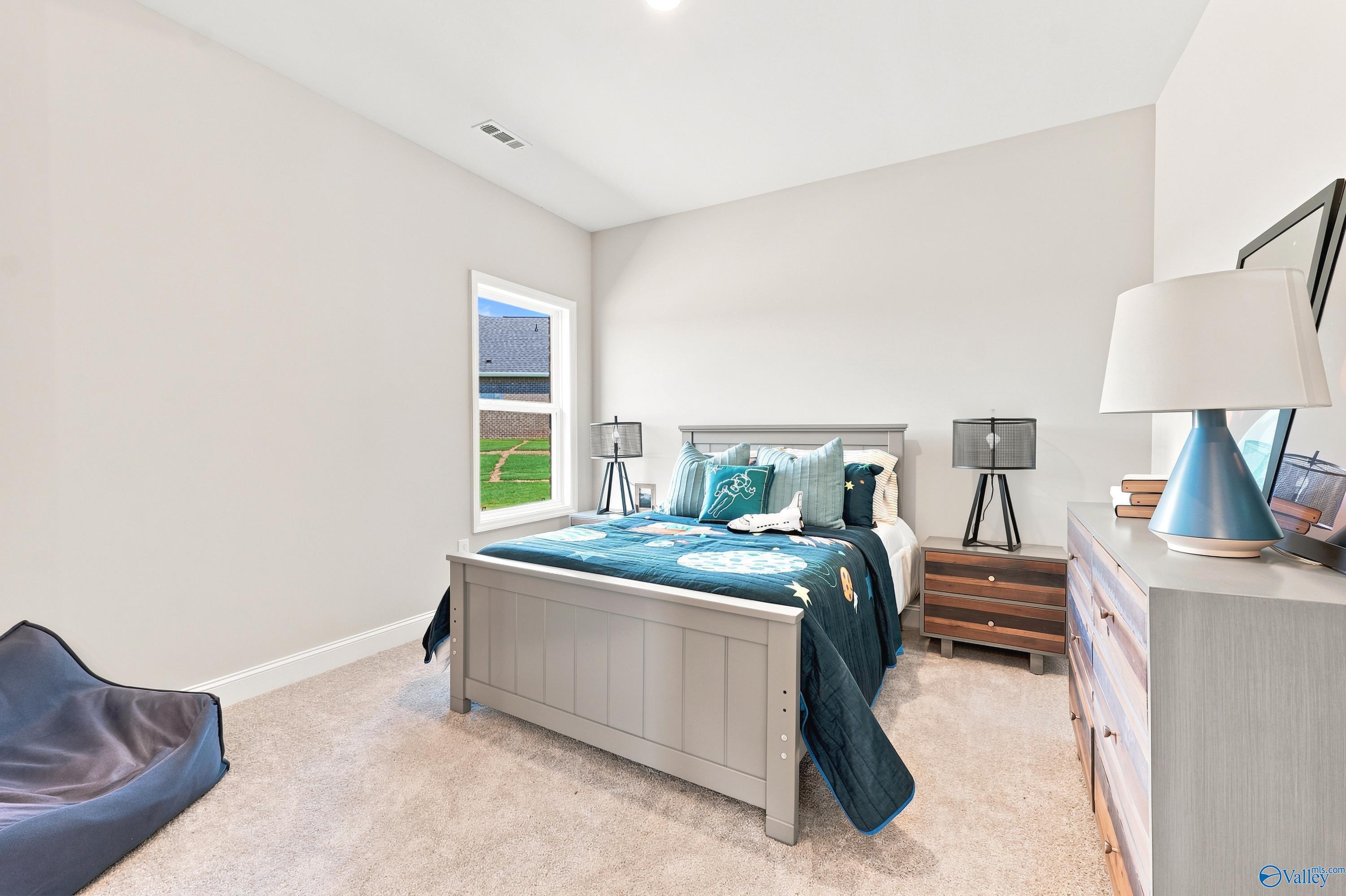 Spacious secondary bedroom with space-themed bedding in The Finleigh floor plan by Davidson Homes in Huntsville, Alabama.