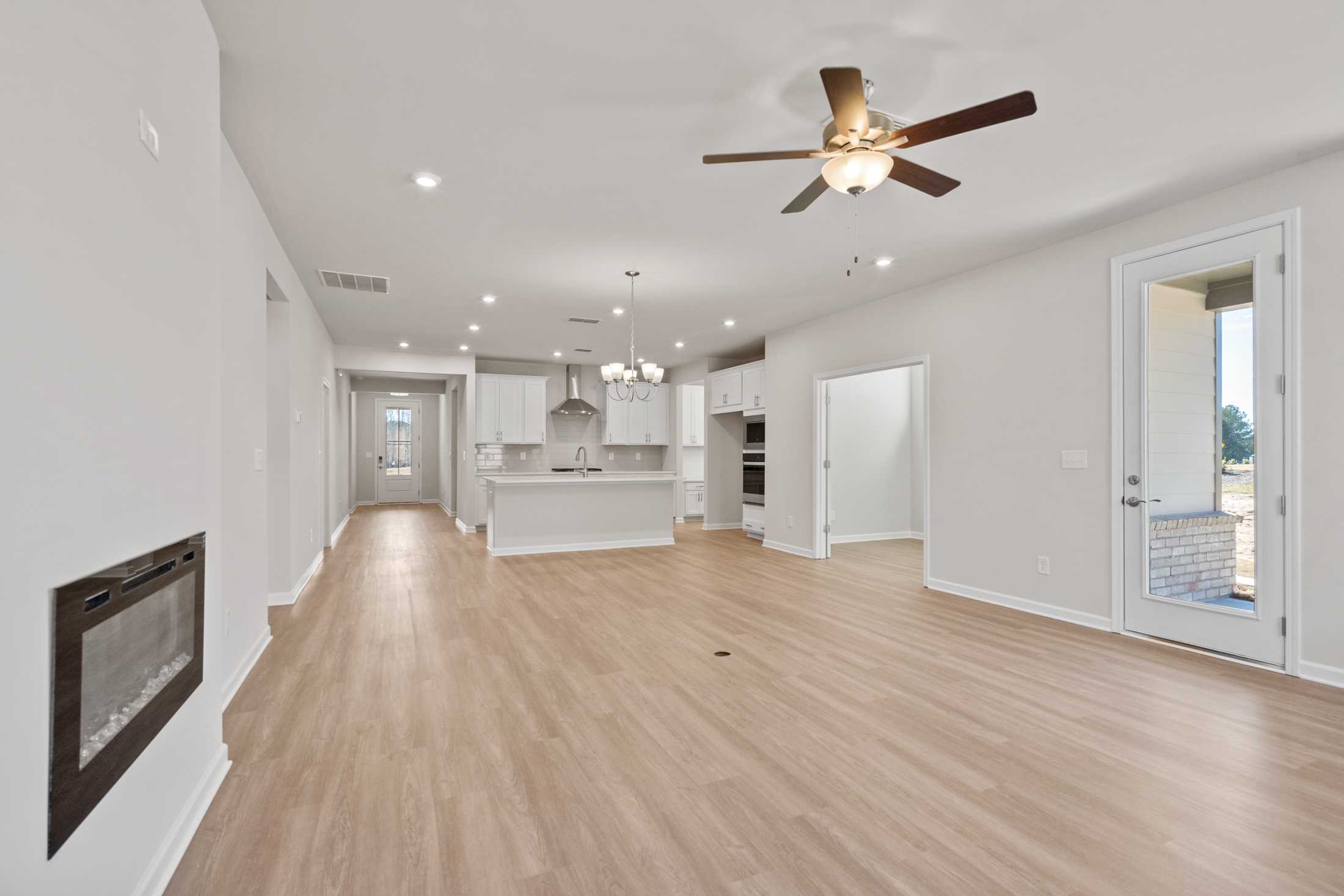 Spacious open-concept kitchen and living area in The Dawson C with white cabinets, large island, gas fireplace, and sliding doors