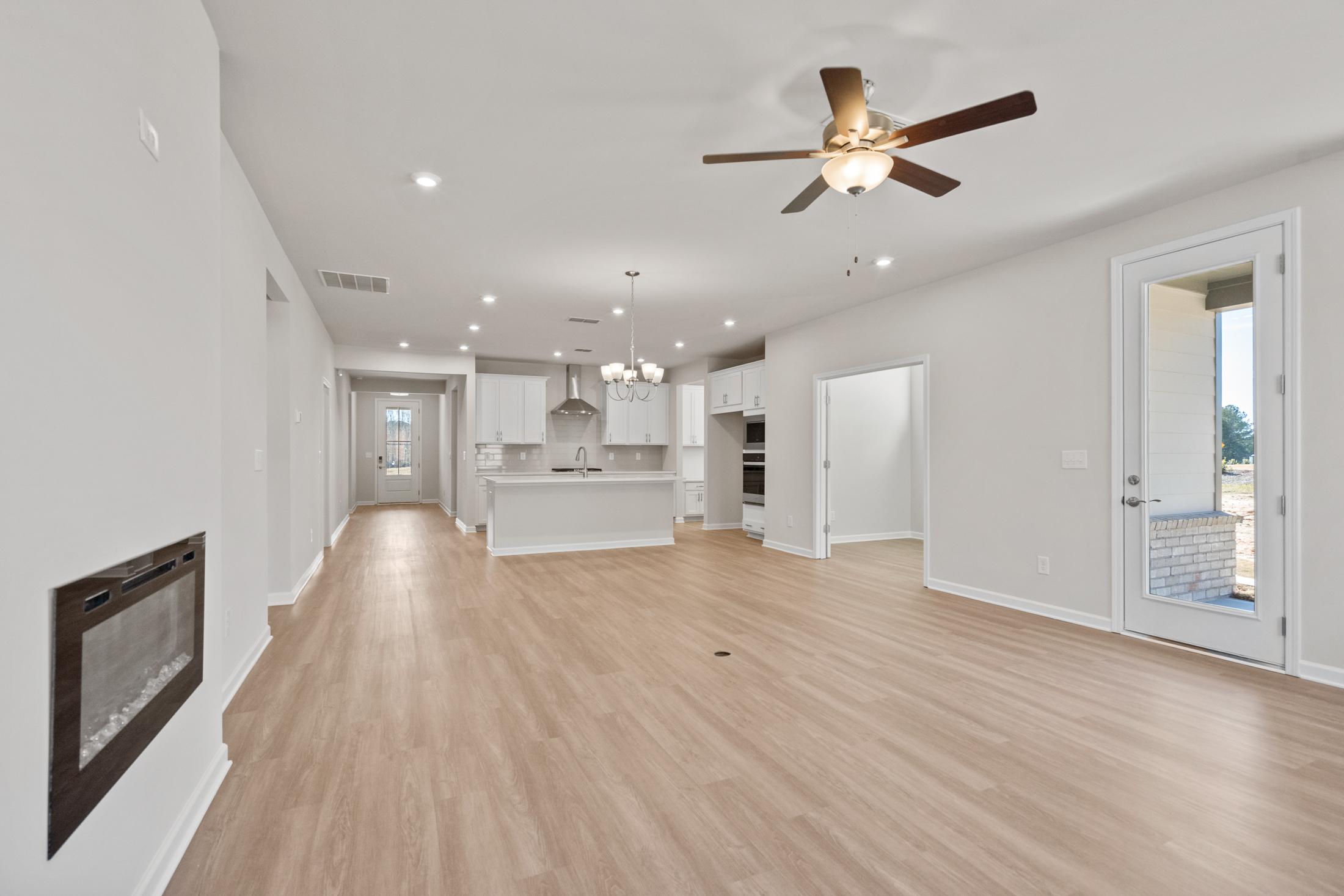 Spacious open-concept kitchen and living area in The Dawson C with white cabinets, large island, gas fireplace, and sliding doors